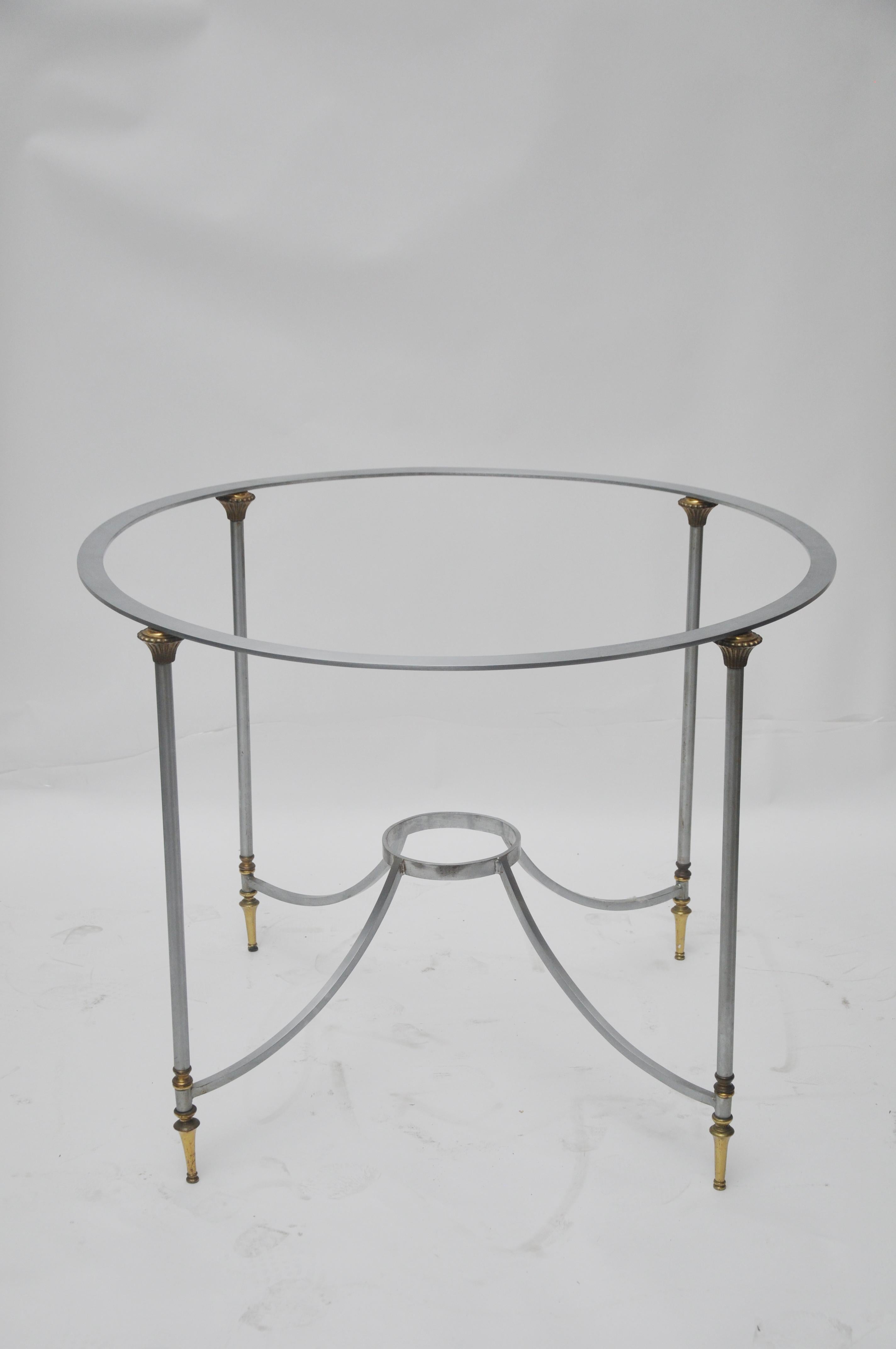 The round table base is both silver and brass. There are brass details at the top and bottom of the legs. This base could support marble or glass top.