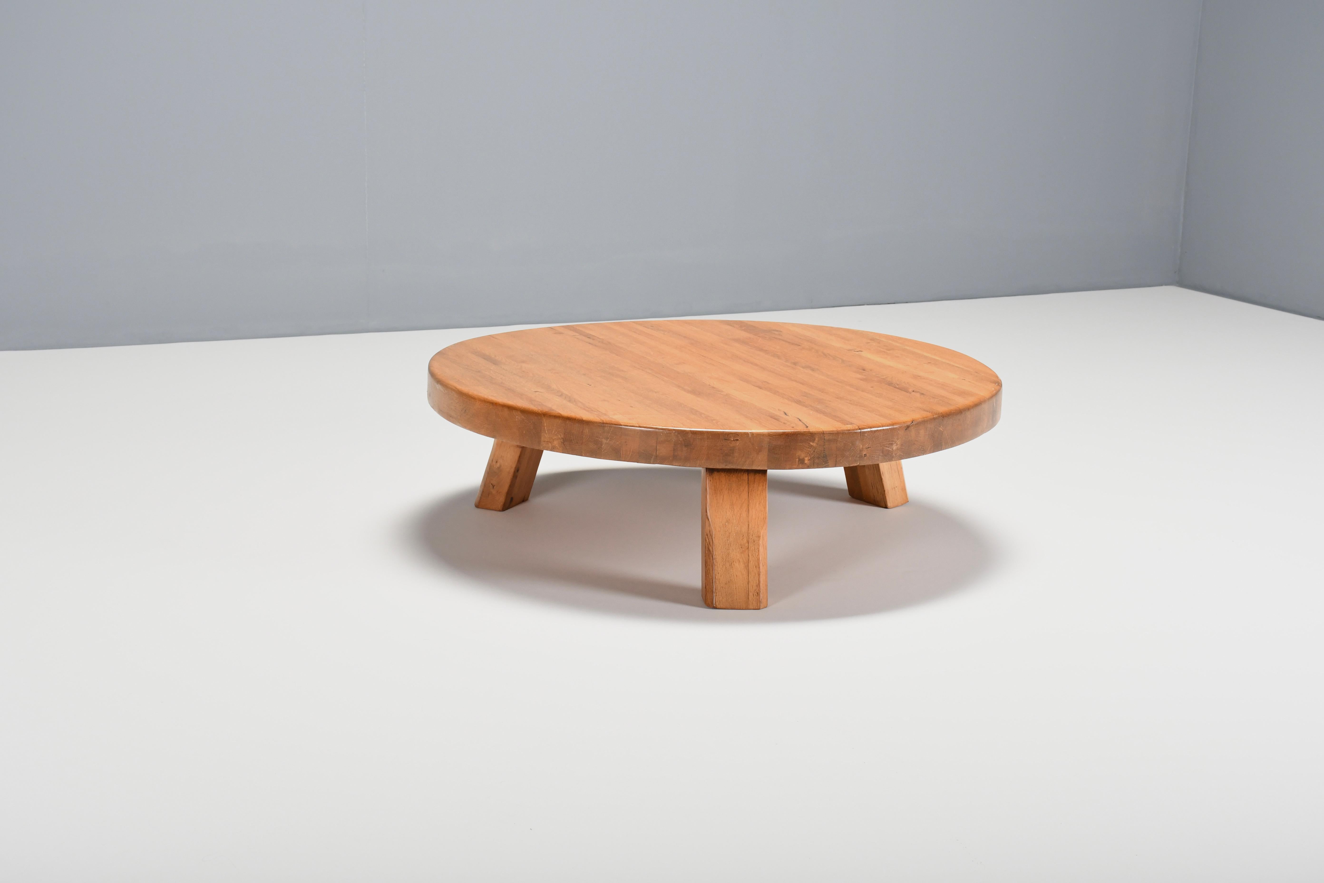 Impressionnante table basse faite à la main en très bon état d'origine. 

La table est fabriquée en chêne français massif. 

Le plateau rond et épais a une belle couleur chaude et est composé de poutres étroites, ce qui donne un bel effet.

La base