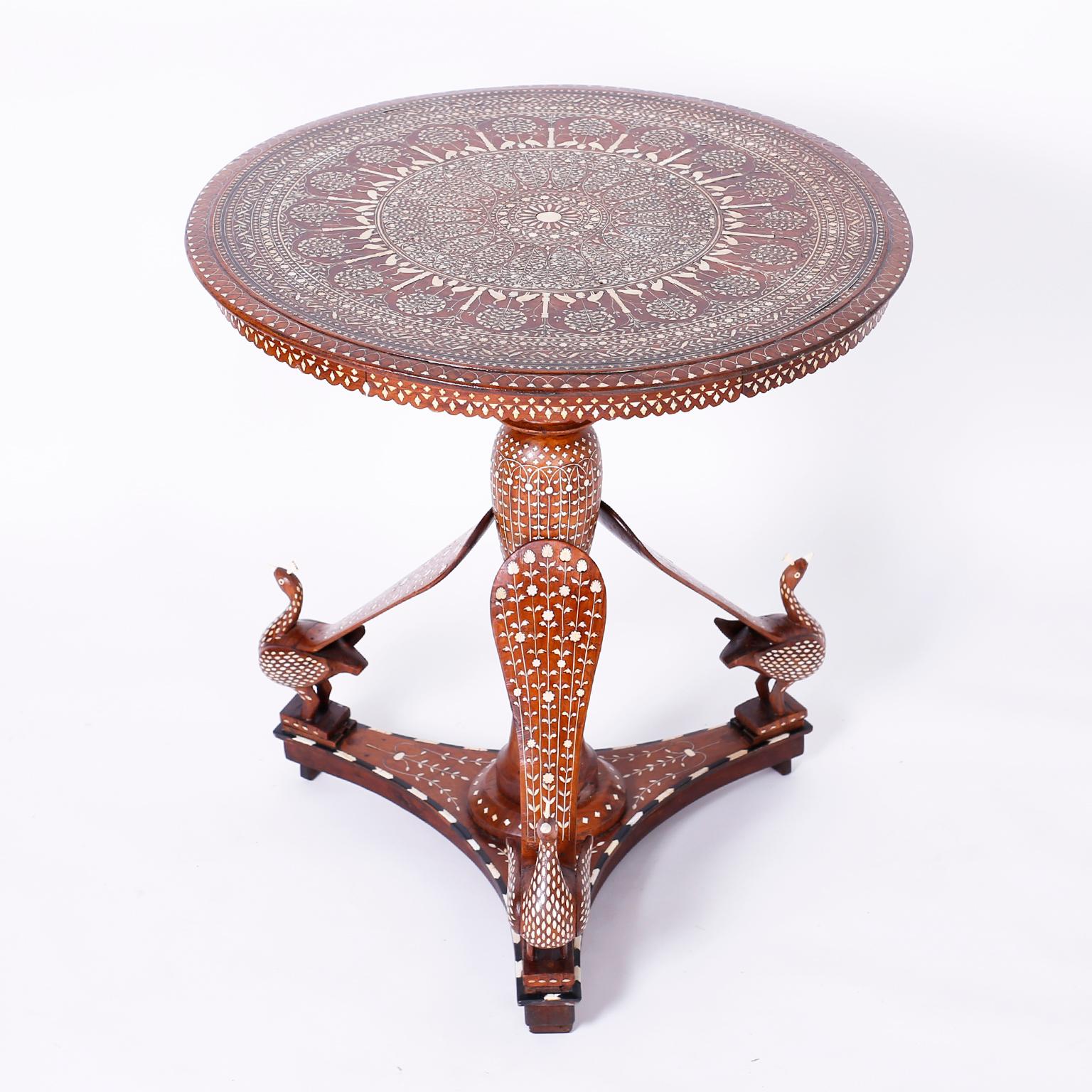 Antique Anglo-Indian table crafted in mahogany ambitiously inlaid with a symbolic floral center medallion surrounded by trees and birds bordered by layers of floral designs.