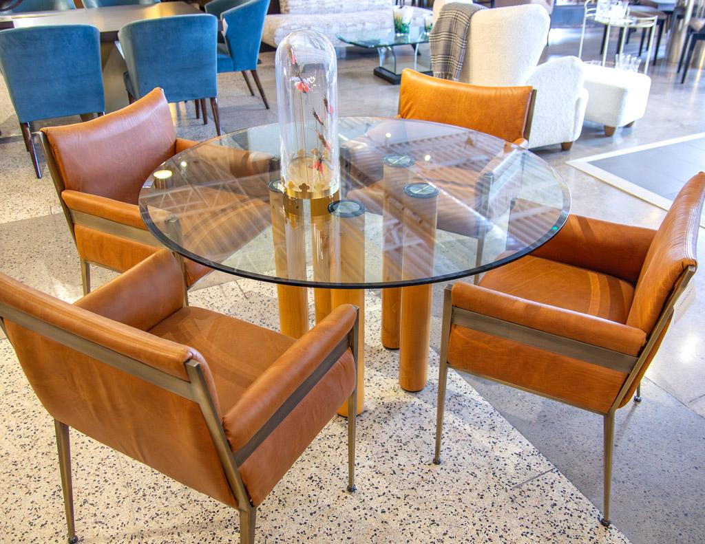 This round glass top modern Italian dining table by the famous designer Ico Parisi and made in Italy in the 1970's, is a stunning piece of modern furniture. Its unique wood leg pillars attach to the glass top using metal rings, giving the table a