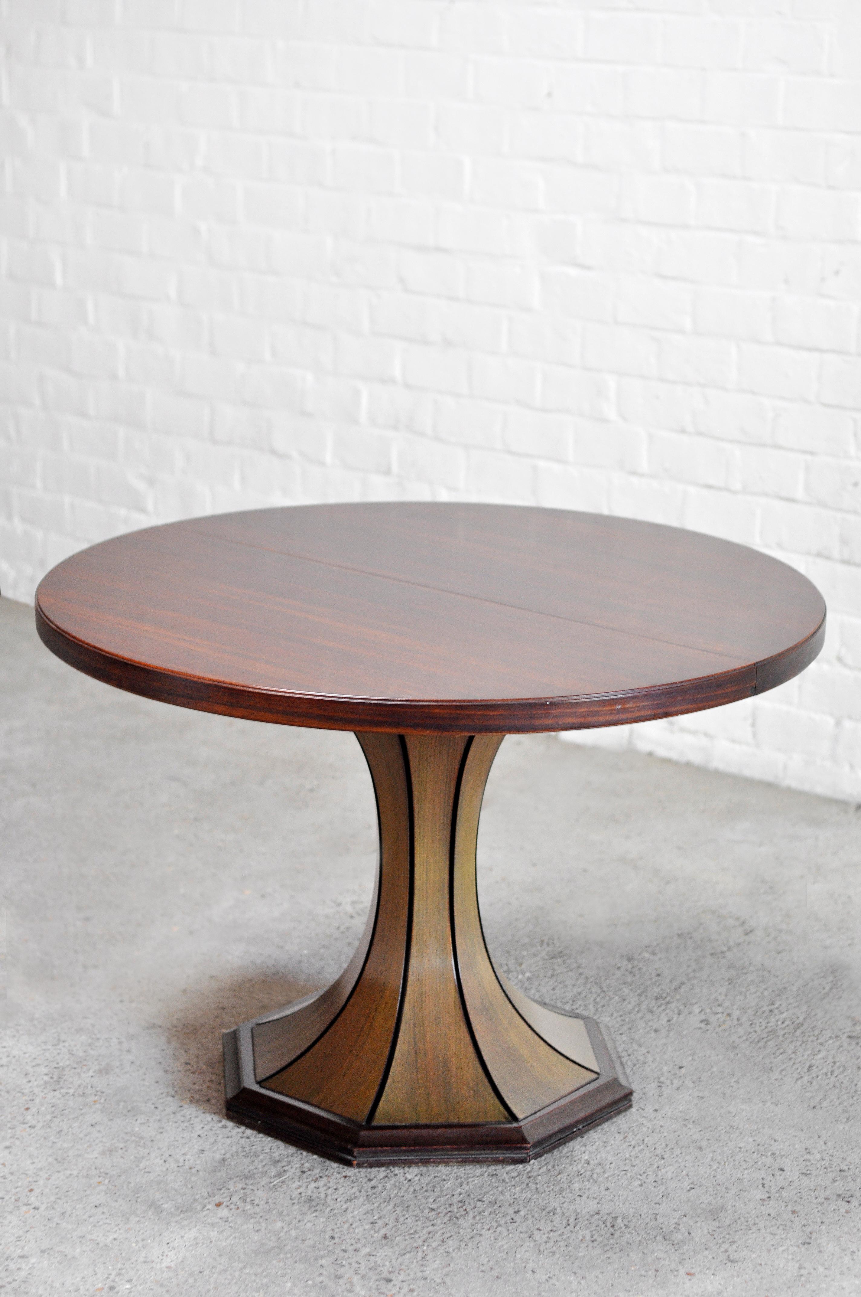 A wonderful Italian round dining table from the 1960s, attributed to Italian designer Carlo De Carli. It features a round mahagony wooden top resting on a sculptural hexagonal base. Amazing grain and shine to the wood. This table is extendable with