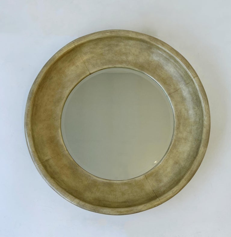 Glamorous 1980’s round aged leather beveled mirror by Maitland Smith.
 Constructed of wood covered with an off white aged leather and beveled mirror.
Shows minor wear consistent with age. 
Retains Maitland Smith label on back. 
Measurements: