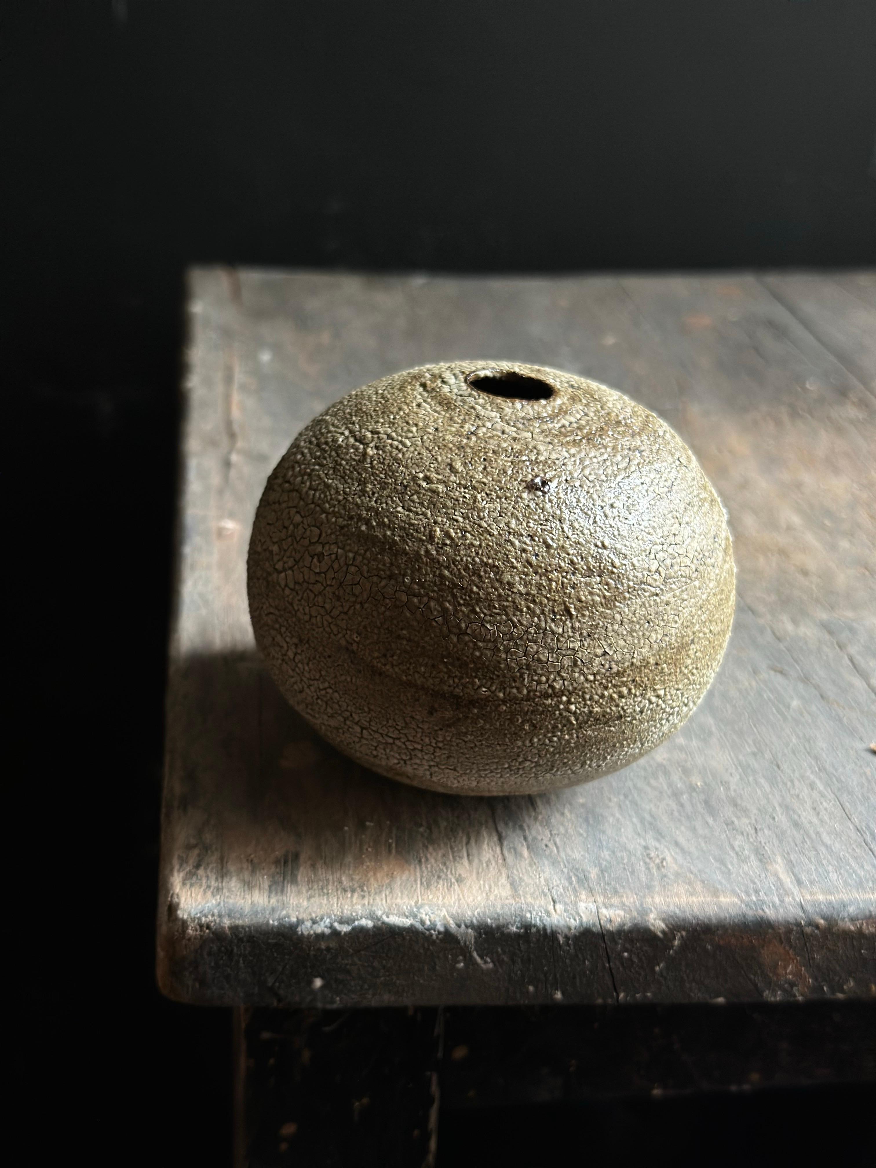 A minimalist spherical bud vase with a crackled glaze finish that reveals fine, organic patterns across its surface. Its neutral, earthy tones and understated elegance make it a versatile addition to contemporary, Japandi, or modern rustic