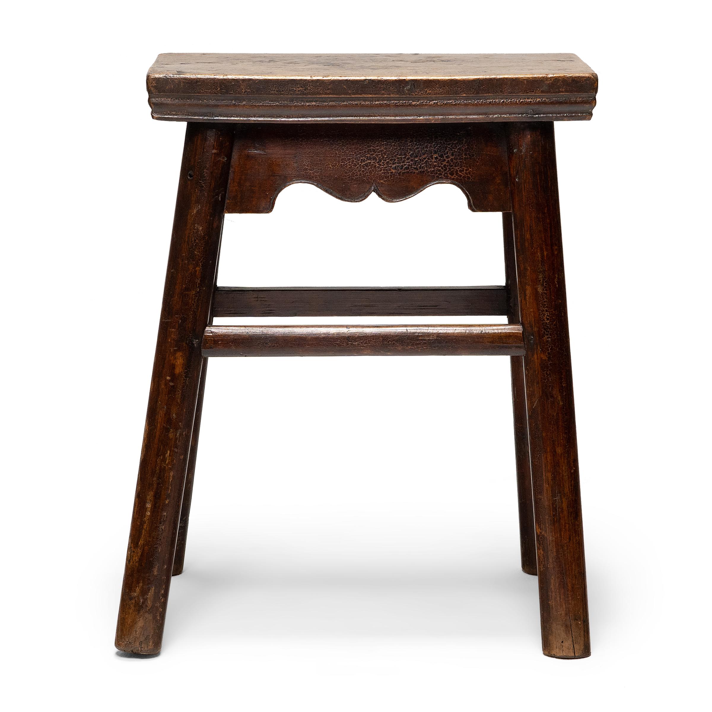 This Chinese courtyard stool dates to the mid-19th century and has a classic splayed leg design with round legs and a rectangular seat. The stool is crafted of northern elmwood (yumu) using traditional mortise and tenon joinery, plus the added
