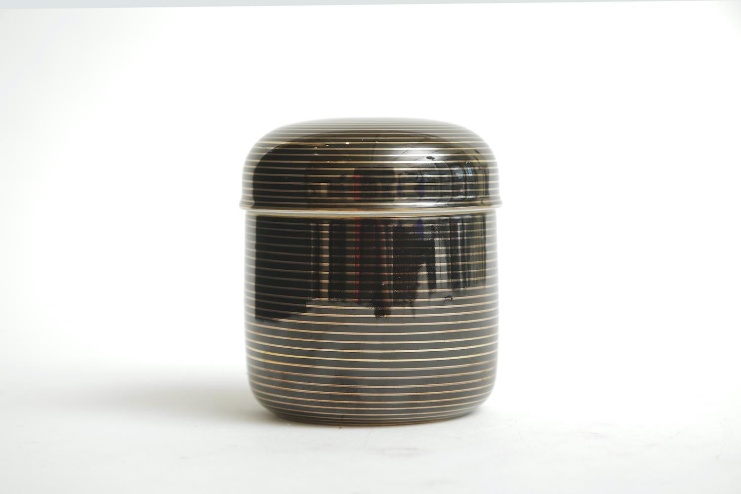 This handsome and rich looking porcelain box has their old label on it that says FF made in Japan. The white porcelain interior and the black and gold exterior with concentric lines and circles make for a great 2-part box. This is from the 1970s.