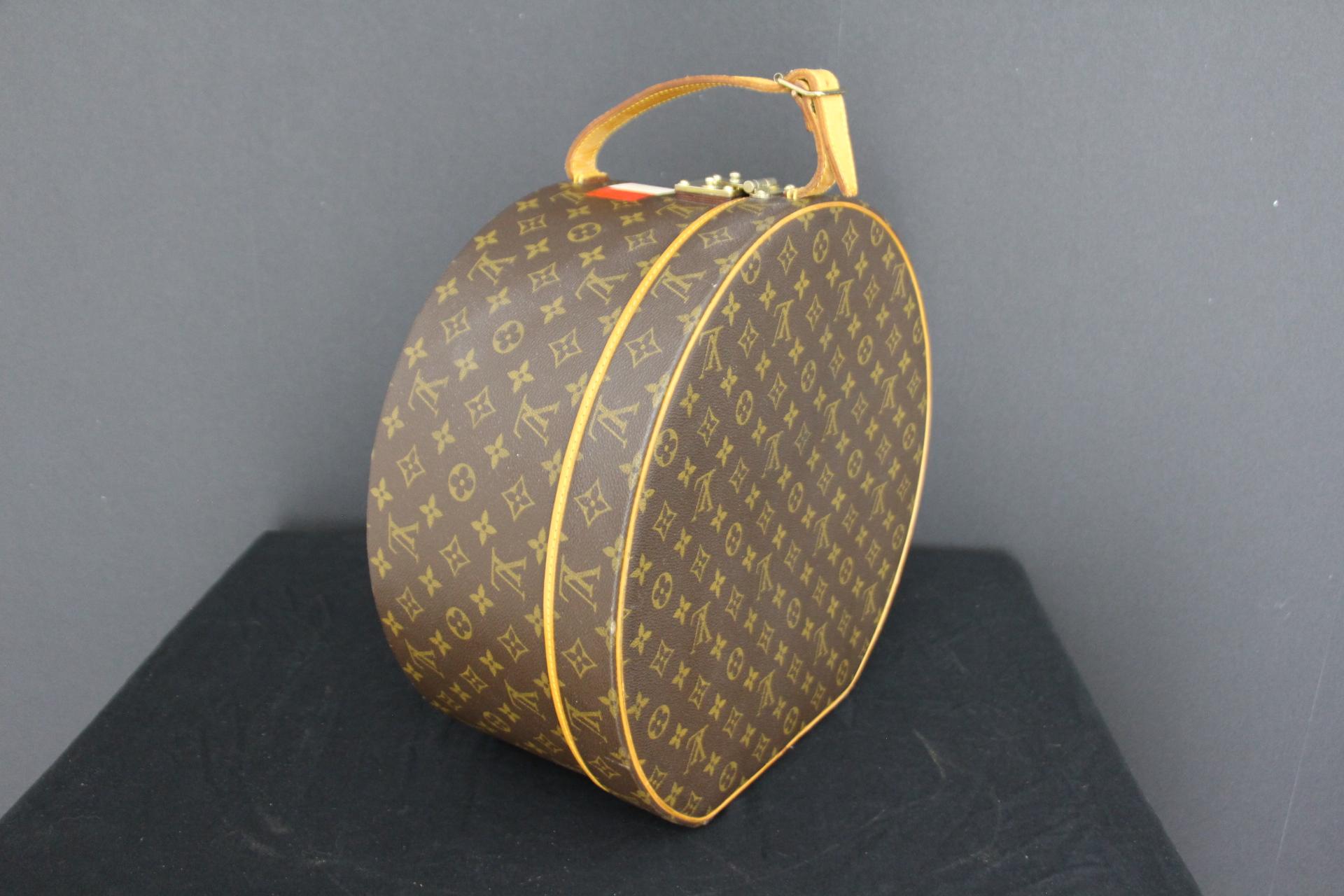 This gorgeous Louis Vuitton hat box features Monogram canvas and natural cowhide reinforcements on a wood structure . It is equipped with an adjustable leather strap . Its leather strap is embossed with its serial number . It has no initials. Its