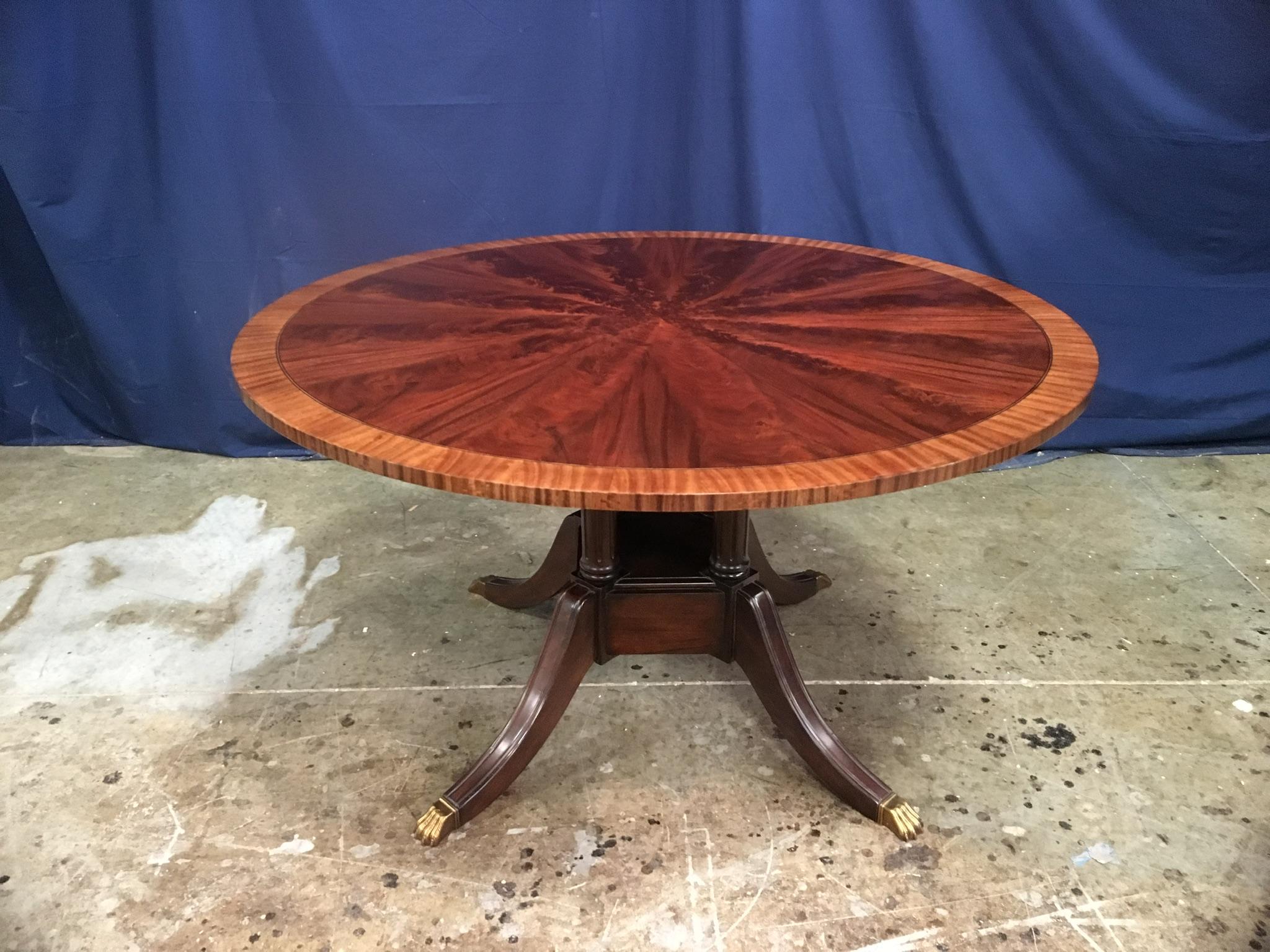 This is made-to-order round traditional mahogany dining table made in the Leighton Hall shop. It features field of radial cut West African swirly crotch mahogany and a border of satinwood. There is an inlay of ebony and white maple which separates