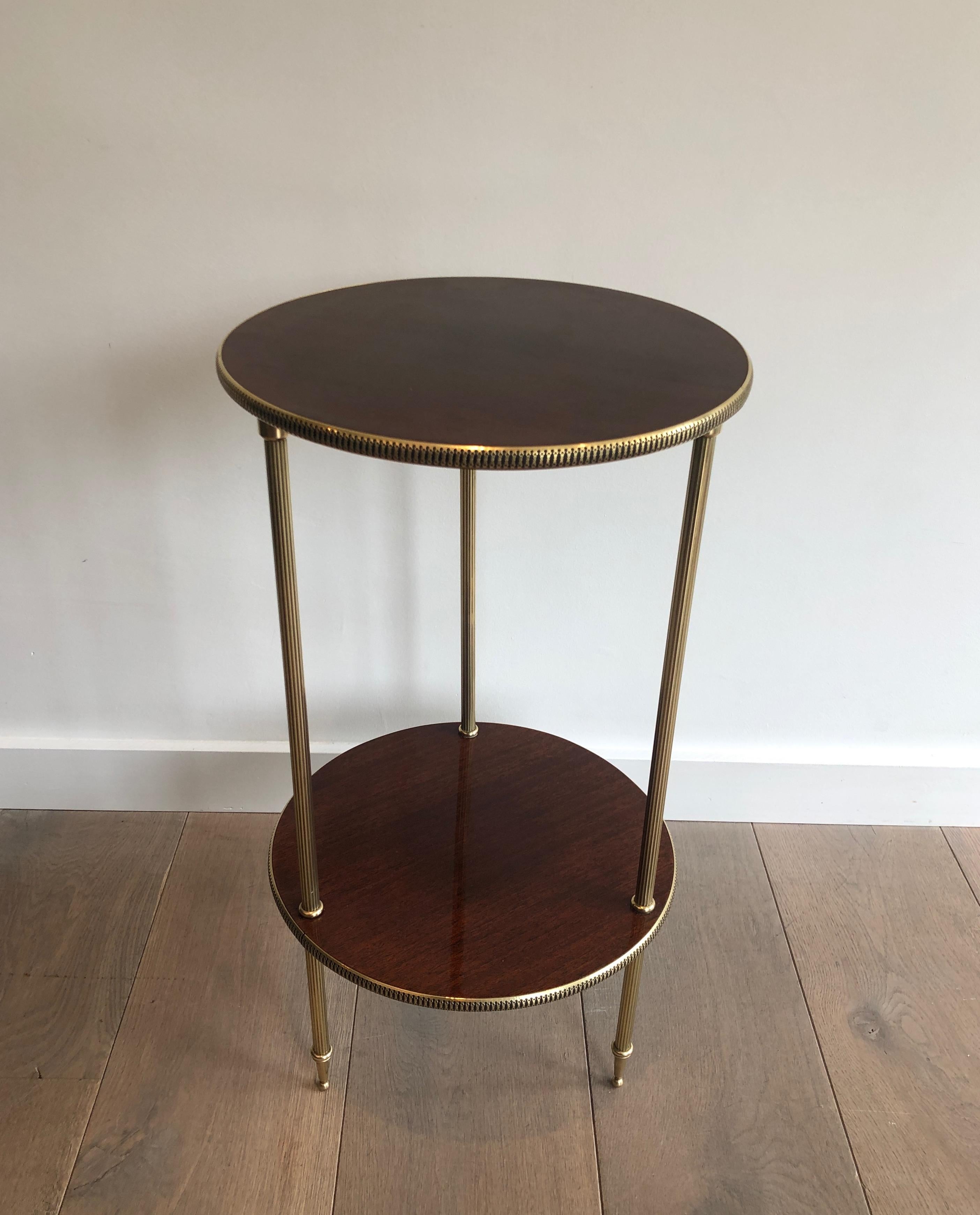 This neoclassical style round side table is made of mahogany trays surrounded by brass decorations and supported by brass feet. It can be used as a Martini table. This is a nice French work, circa 1950.