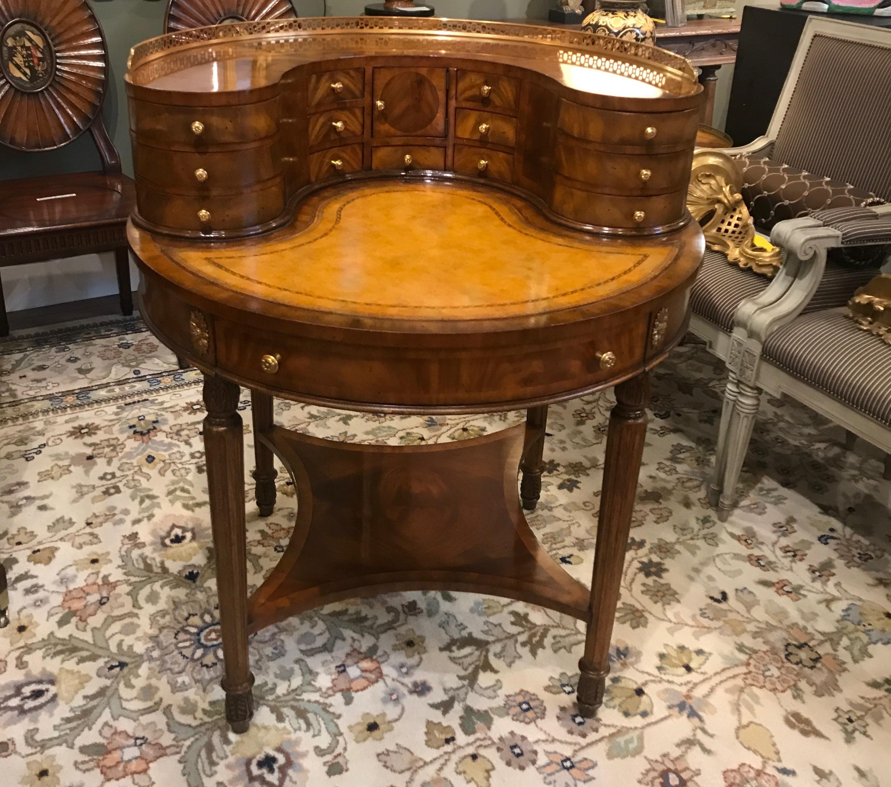Unusual round desk by Maitland Smith, the mahogany and walnut medium toned wood with pierced brass gallery on the upper drawers in a Carlton house design. The writing surface covered in tooled leather.