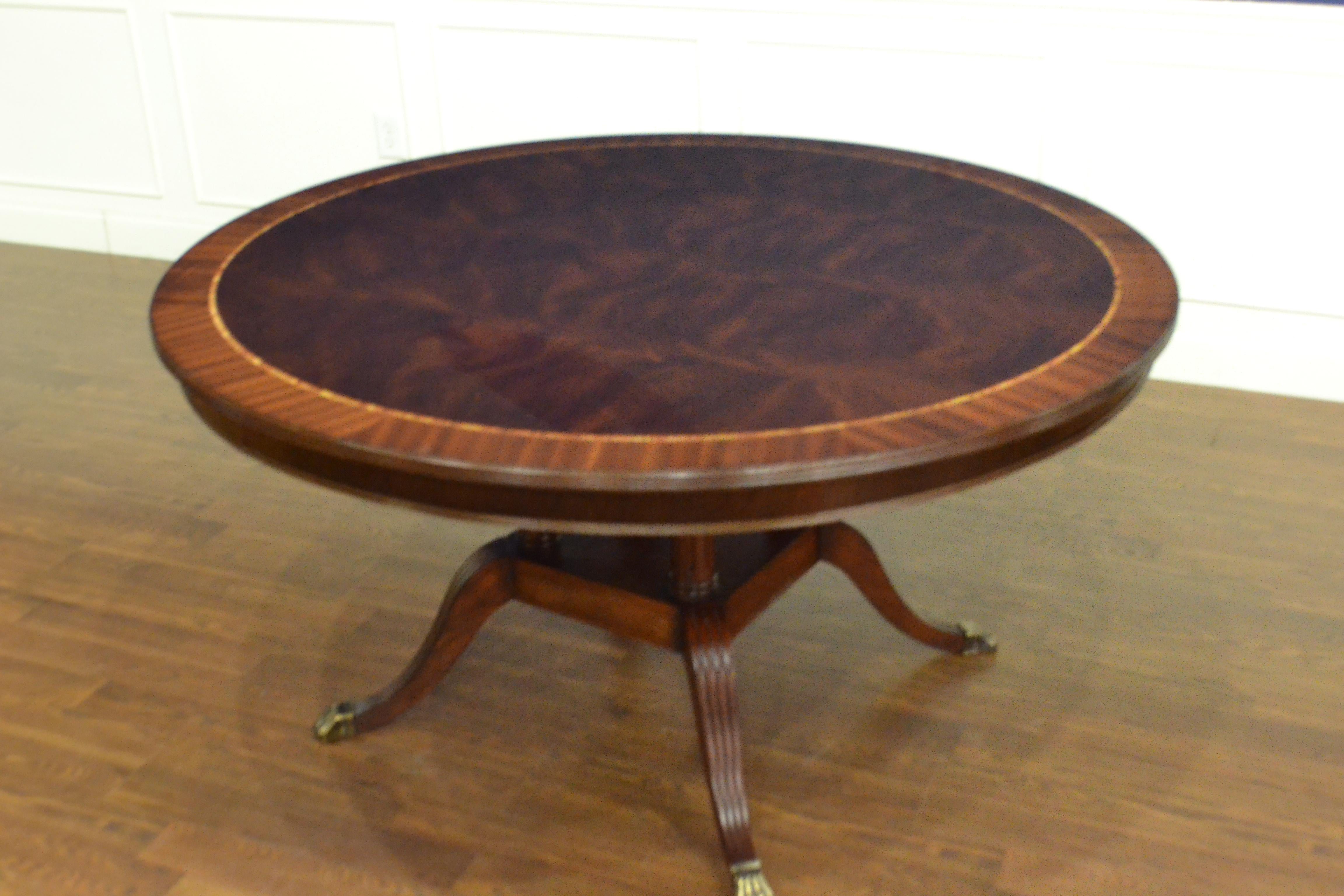This is made-to-order round traditional mahogany dining table made in the Leighton Hall shop. It features field of West African swirly crotch mahogany and a border of straight grain mahogany. There is an inlay of tulipwood which separates the field