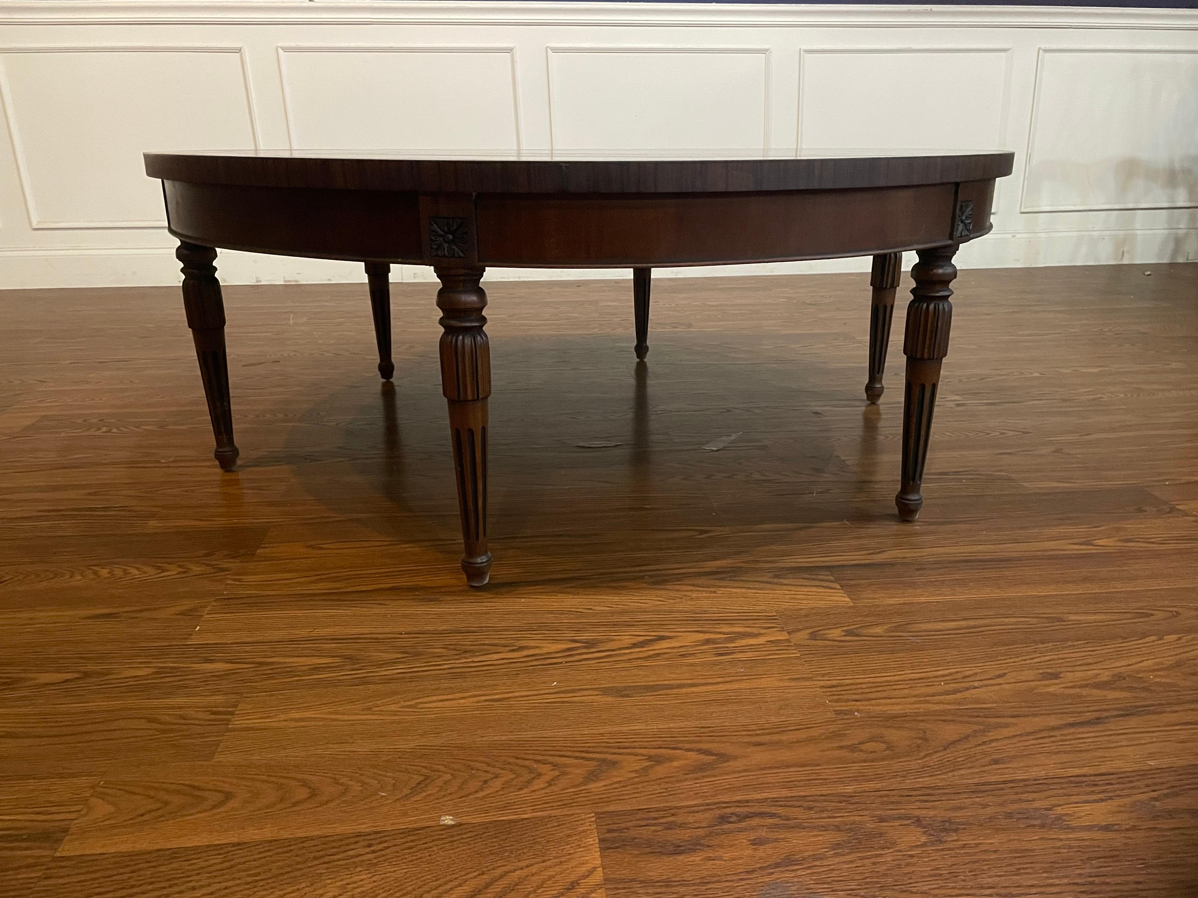 This is a made-to-order round traditional mahogany coffee table made in the Leighton Hall shop. It features swirly crotch mahogany and borders of straight grain mahogany and santos rosewood (Pau Ferro). It has six Sheraton inspired round fluted