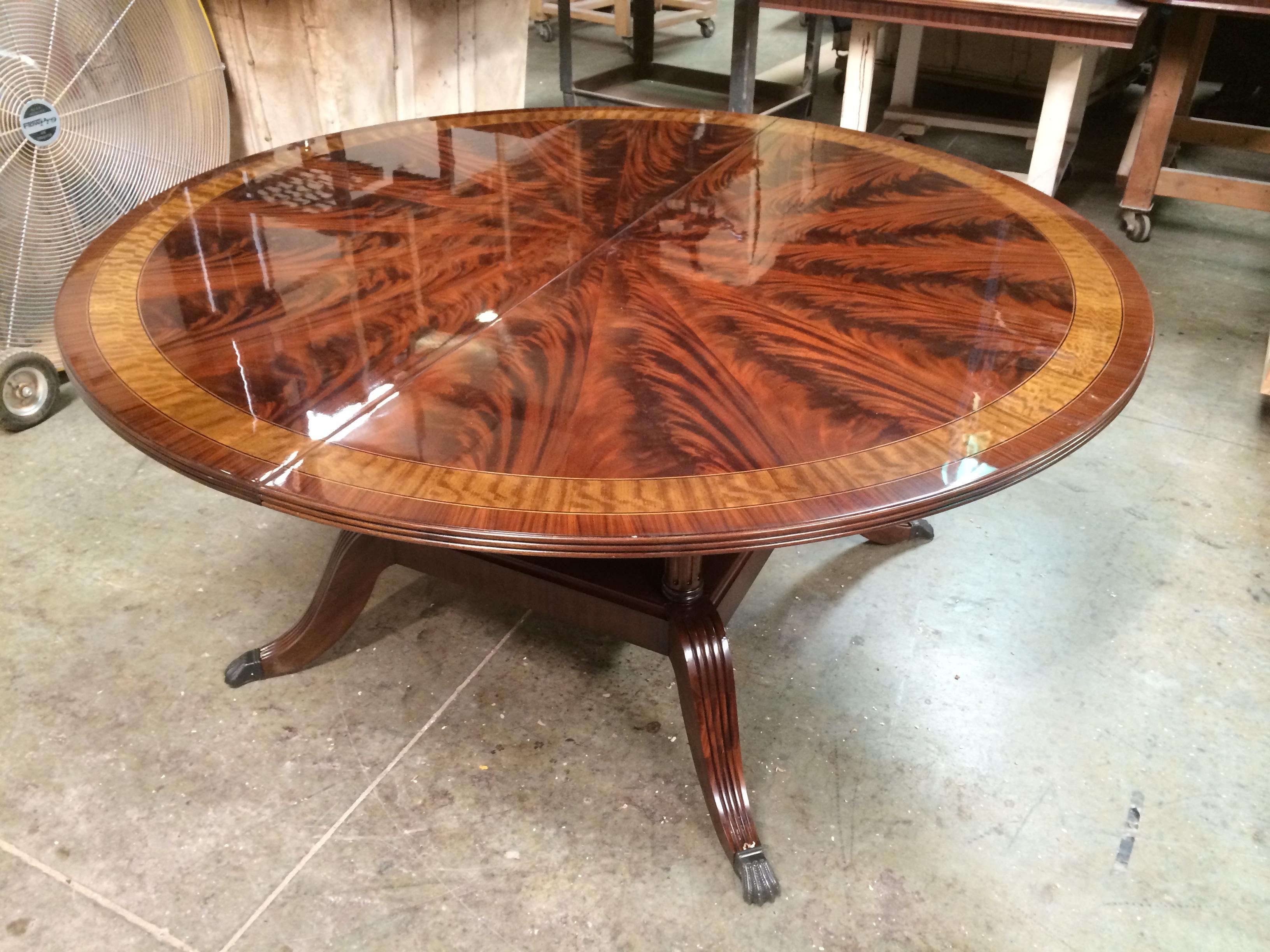 This is made-to-order round traditional mahogany dining table made in the Leighton Hall shop. It features a radial cut field of West African swirly crotch mahogany and two borders of satinwood and Santos rosewood. The top has a hand rubbed and