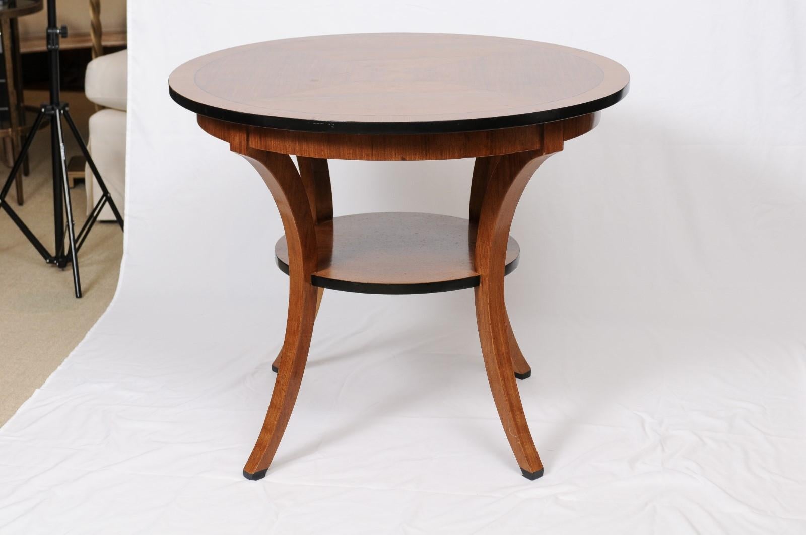 Mahogany round table that could be used for many purposes as a small dining table or an end or side table. An Italian reproduction featuring a veneered top with border, on four cabriole legs with a shelf.