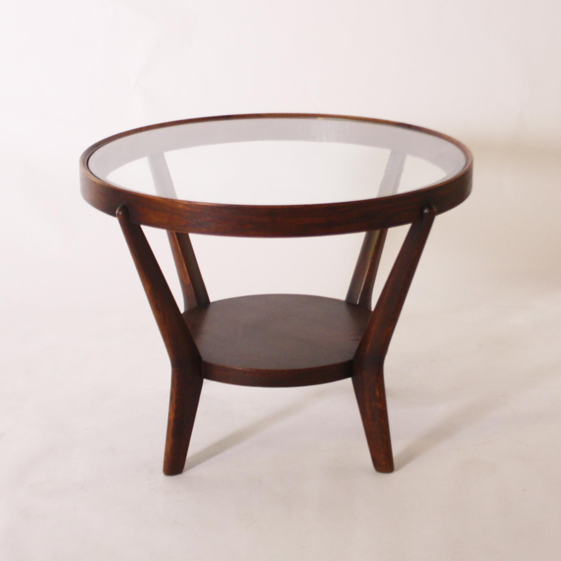 Round mahogany table with glass top, circa 1950.