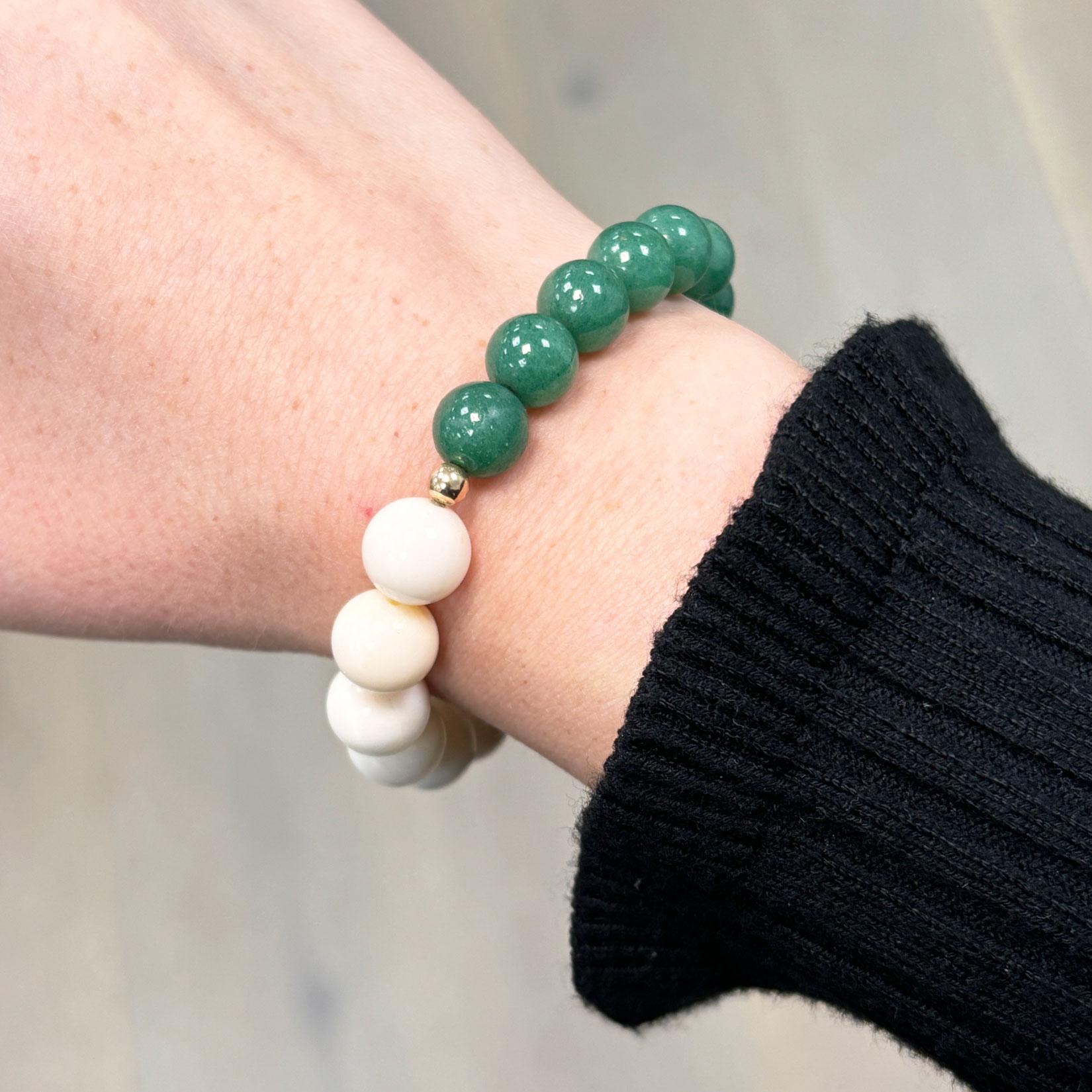 This elegant stretch bracelet showcases a captivating contrast between rich green malachite and smooth white coral beads, handcrafted into a seamless, rounded design. Accented with polished 14k yellow gold spacers, it strikes the perfect balance