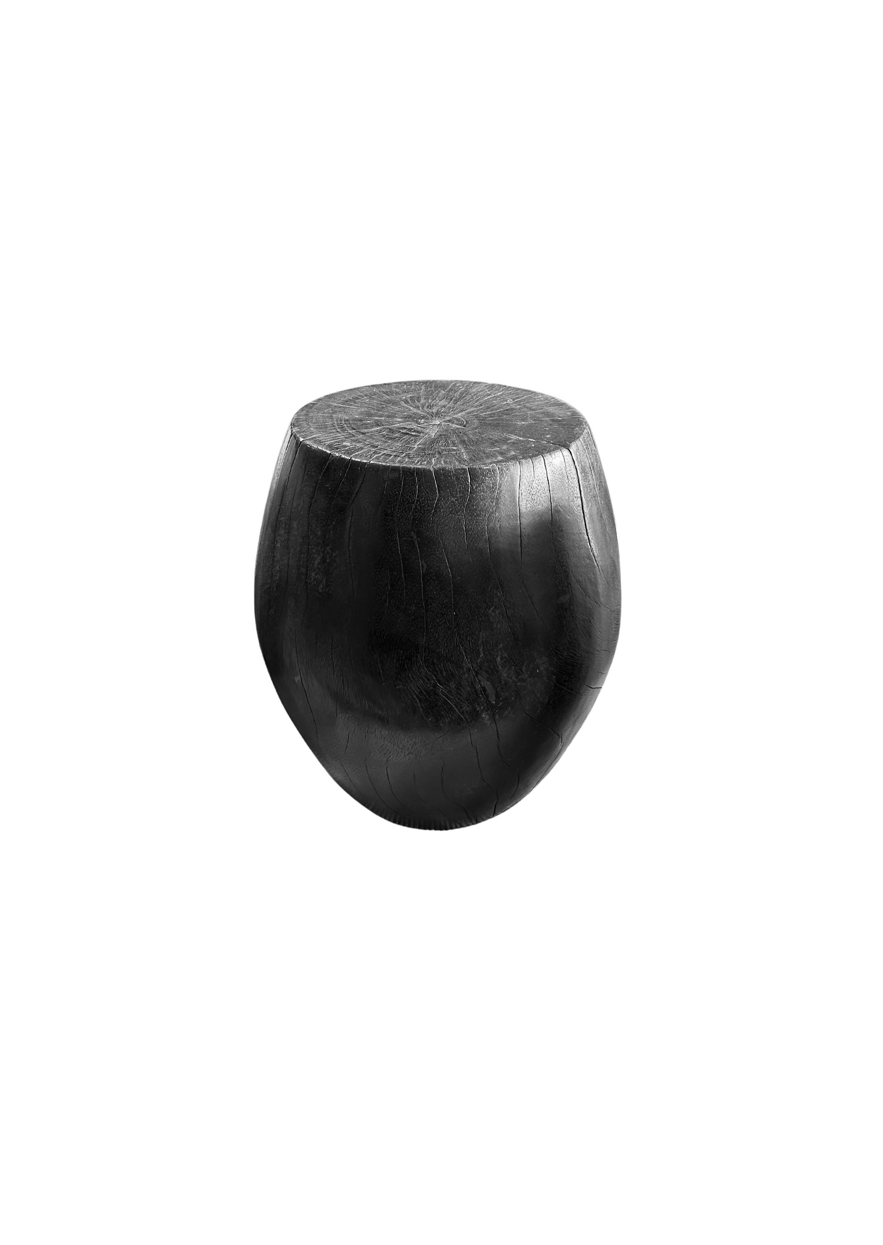 A wonderfully sculpted side table, crafted from a single block of mango wood. It features wonderful wood textures. To achieve its dark black pigment the wood was burnt numerous times and finished with a clear coat. 

Height 46cm x Diameter 30cm at