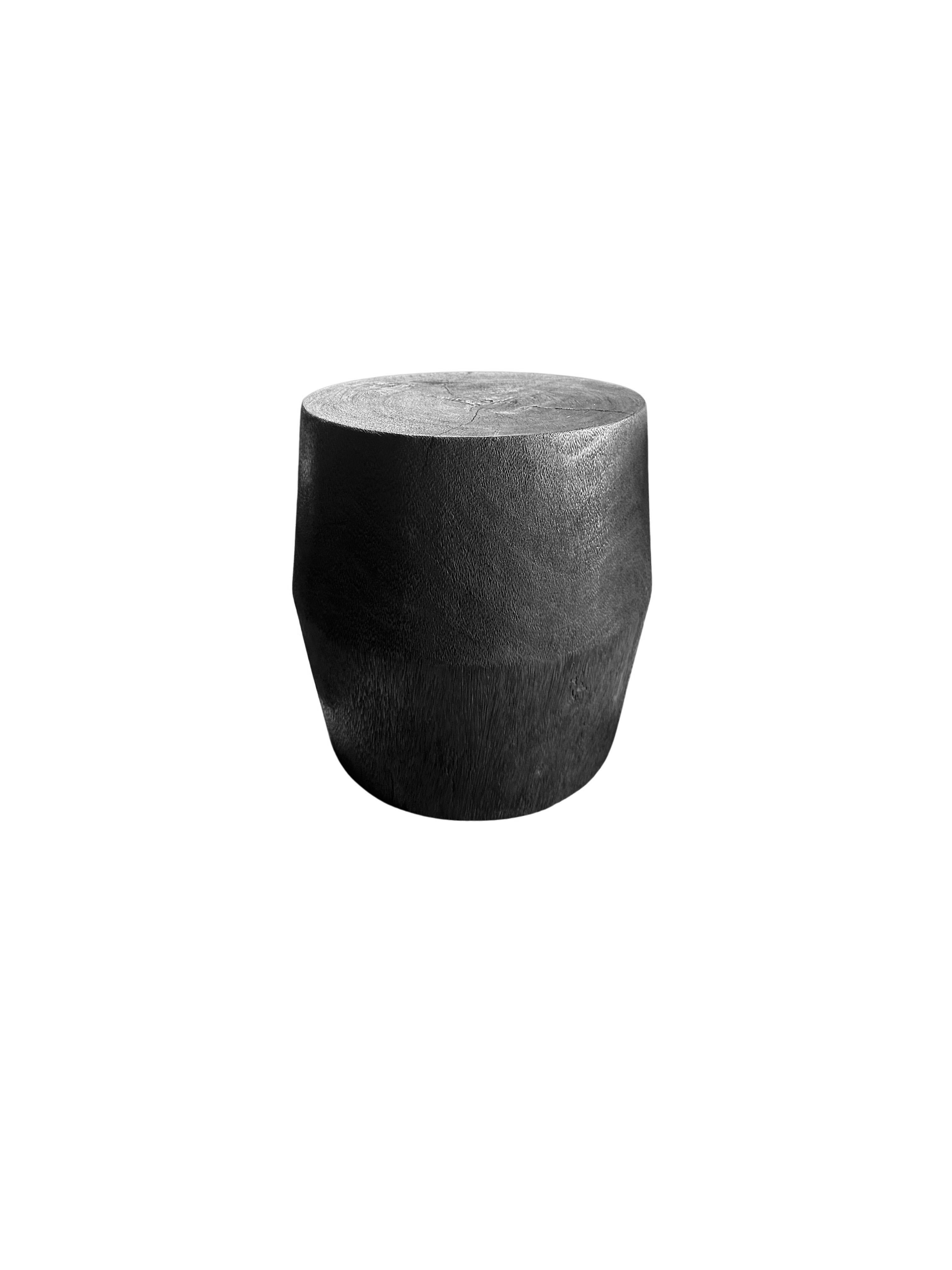 Une table d'appoint merveilleusement sculptée, fabriquée à partir d'un seul bloc de bois de manguier. Il présente de merveilleuses textures de bois. Pour obtenir son pigment noir foncé, le bois a été brûlé de nombreuses fois et terminé par une