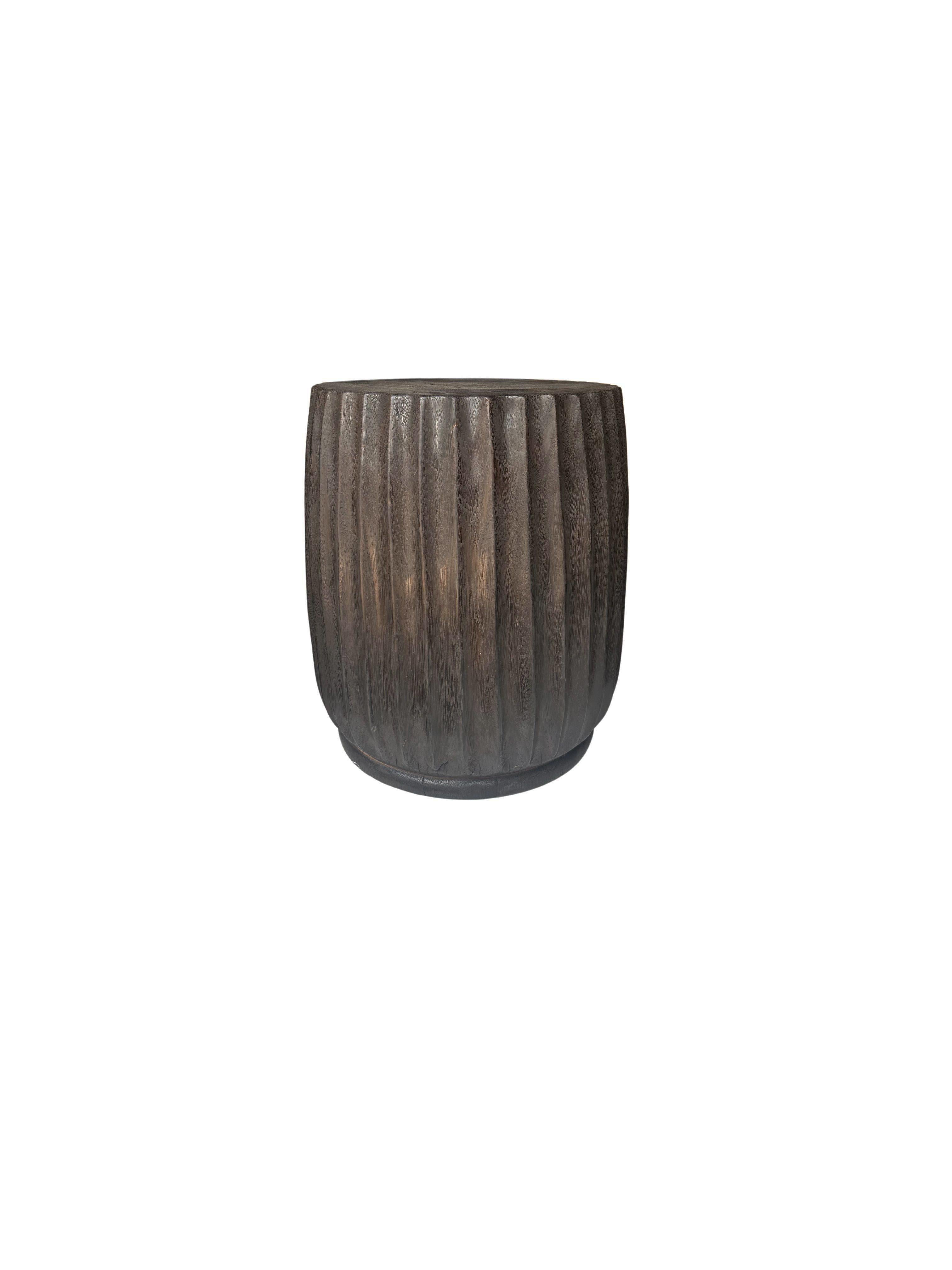 Ein wunderschön geformter Beistelltisch, der aus einem einzigen Block Mangoholz gefertigt ist. Es weist wunderbare Holztexturen auf. Dieser Tisch weist geschnitzte Details auf, die sich um seine Seiten herum erstrecken. Um das dunkelbraune Finish zu