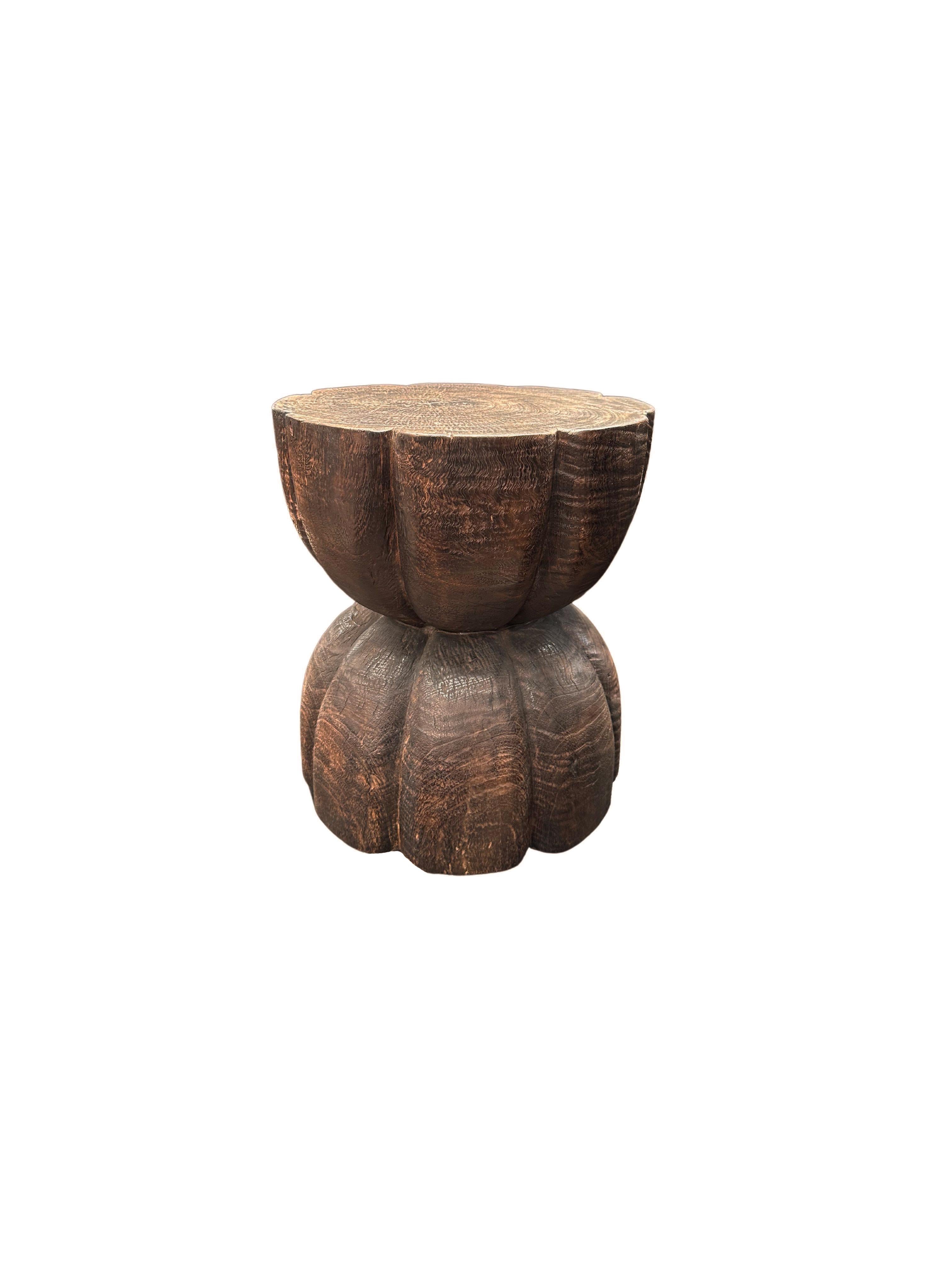 Une table d'appoint merveilleusement sculptée, fabriquée à partir d'un seul bloc de bois de manguier. Il présente de merveilleuses textures de bois. Cette table présente des détails sculptés qui enveloppent ses côtés. Pour obtenir sa finition brun