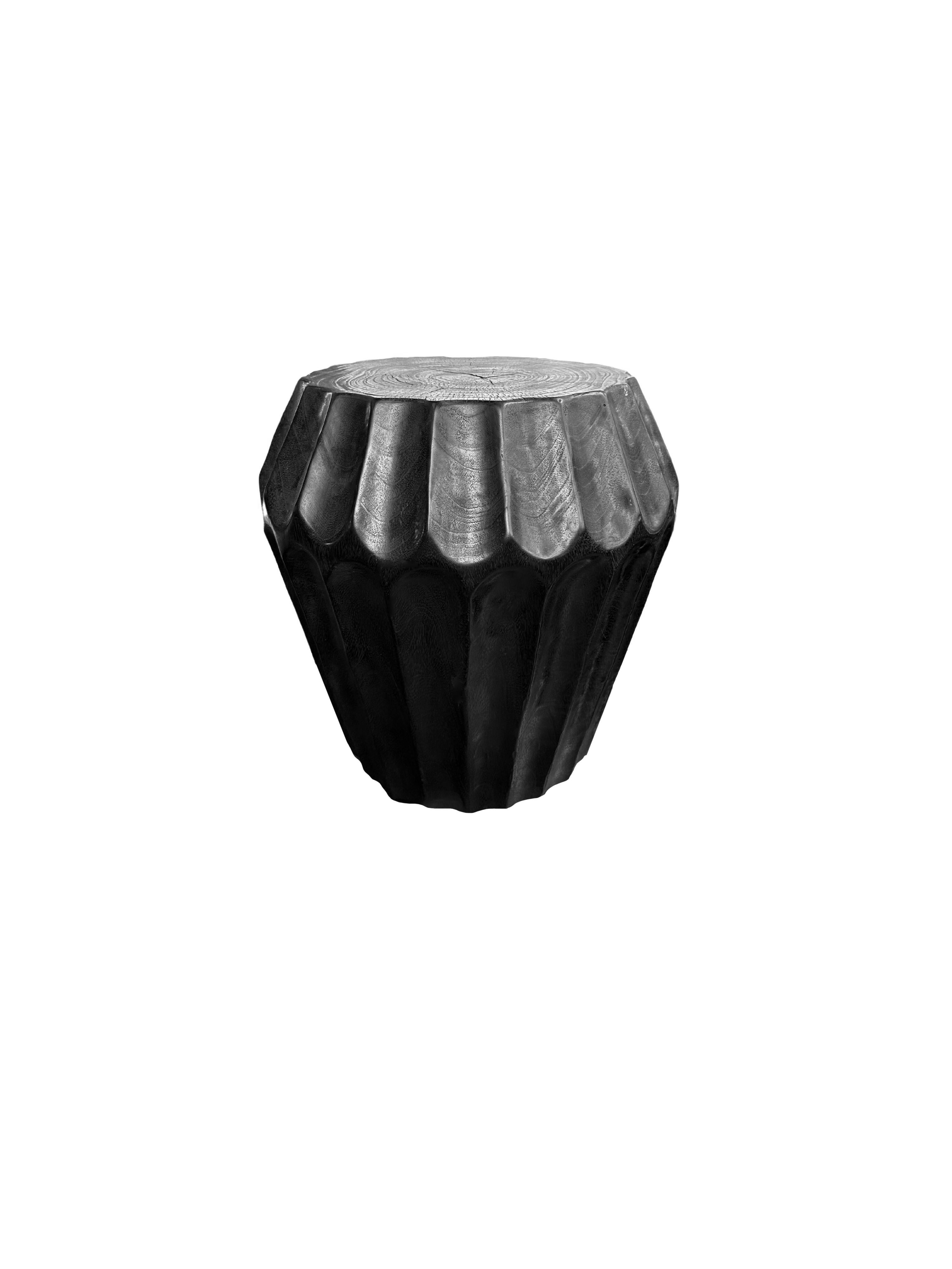 Une table d'appoint merveilleusement sculptée, fabriquée à partir d'un seul bloc de bois de manguier. Il présente de merveilleuses textures de bois. Cette table présente des détails sculptés qui enveloppent ses côtés. Pour obtenir sa finition