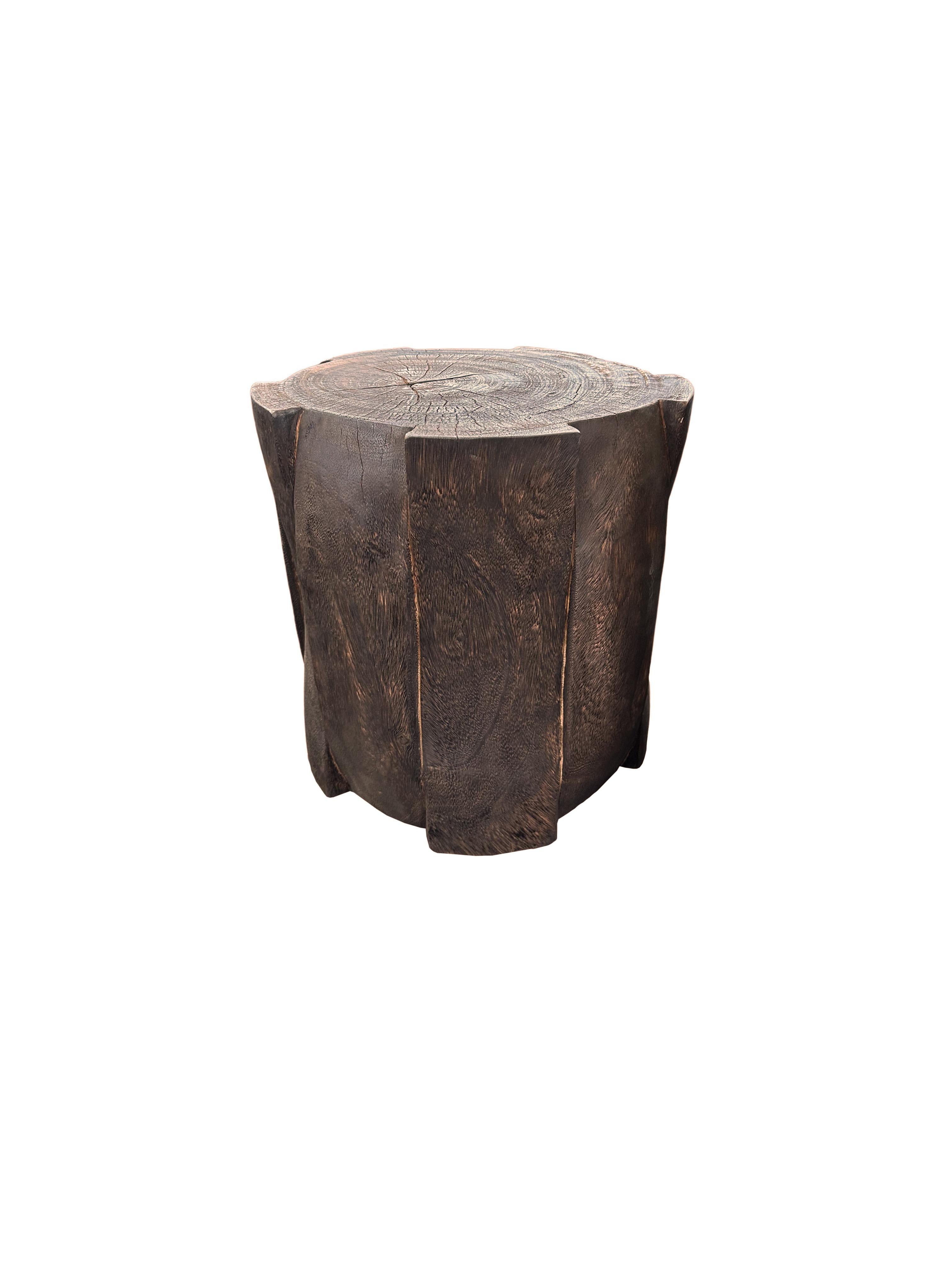 A wonderfully sculpted side table, crafted from a single block of mango wood. It features wonderful wood textures. This table features carved detailing that wraps around its sides, inspired by woven bamboo. To achieve its espresso pigment