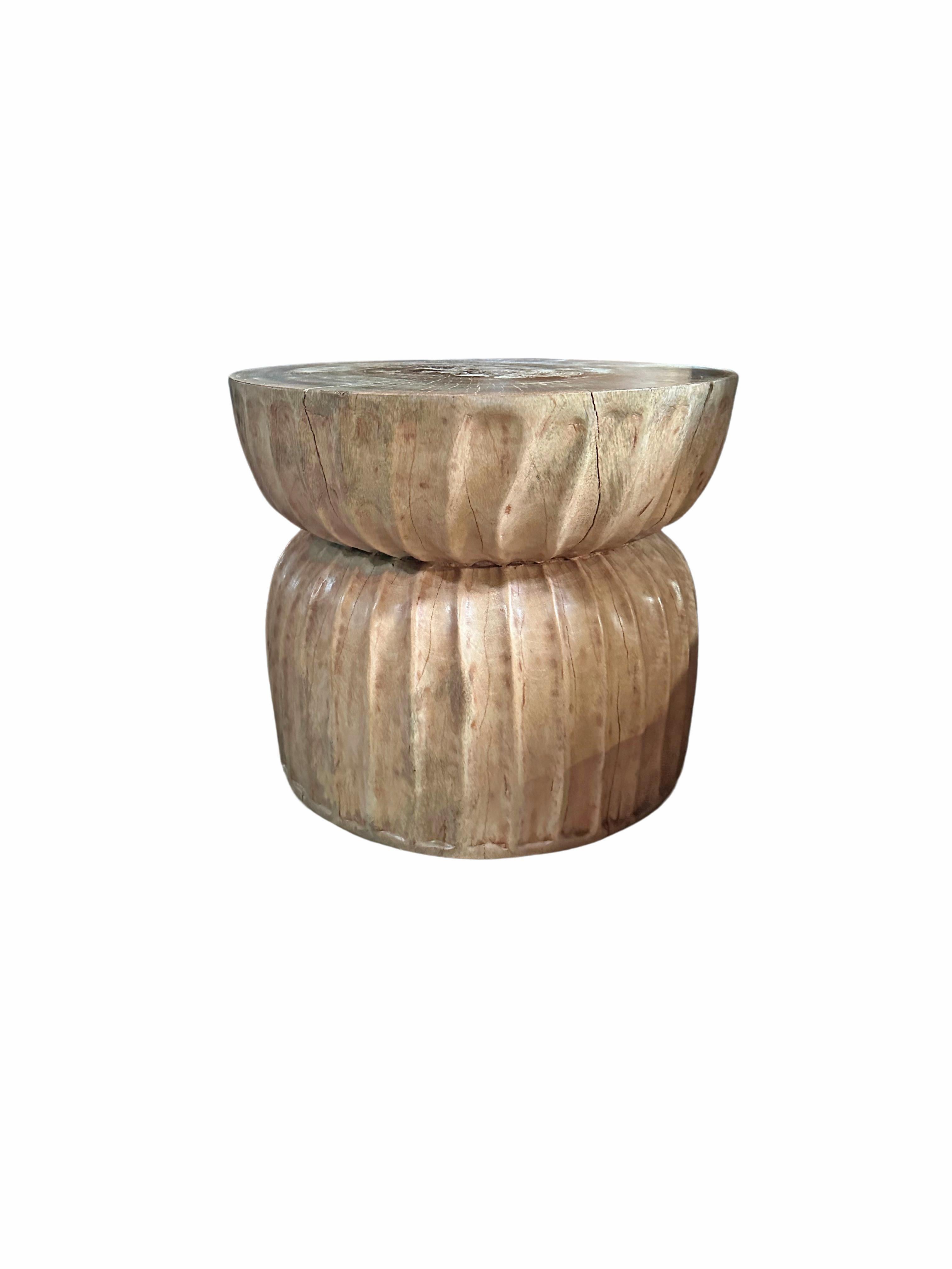 A wonderfully sculpted side table, crafted from a single block of mango wood. It features wonderful wood textures as well and carved detailing that wrap around its sides. The item was sanded and smoothed allowing for a natural finish.
