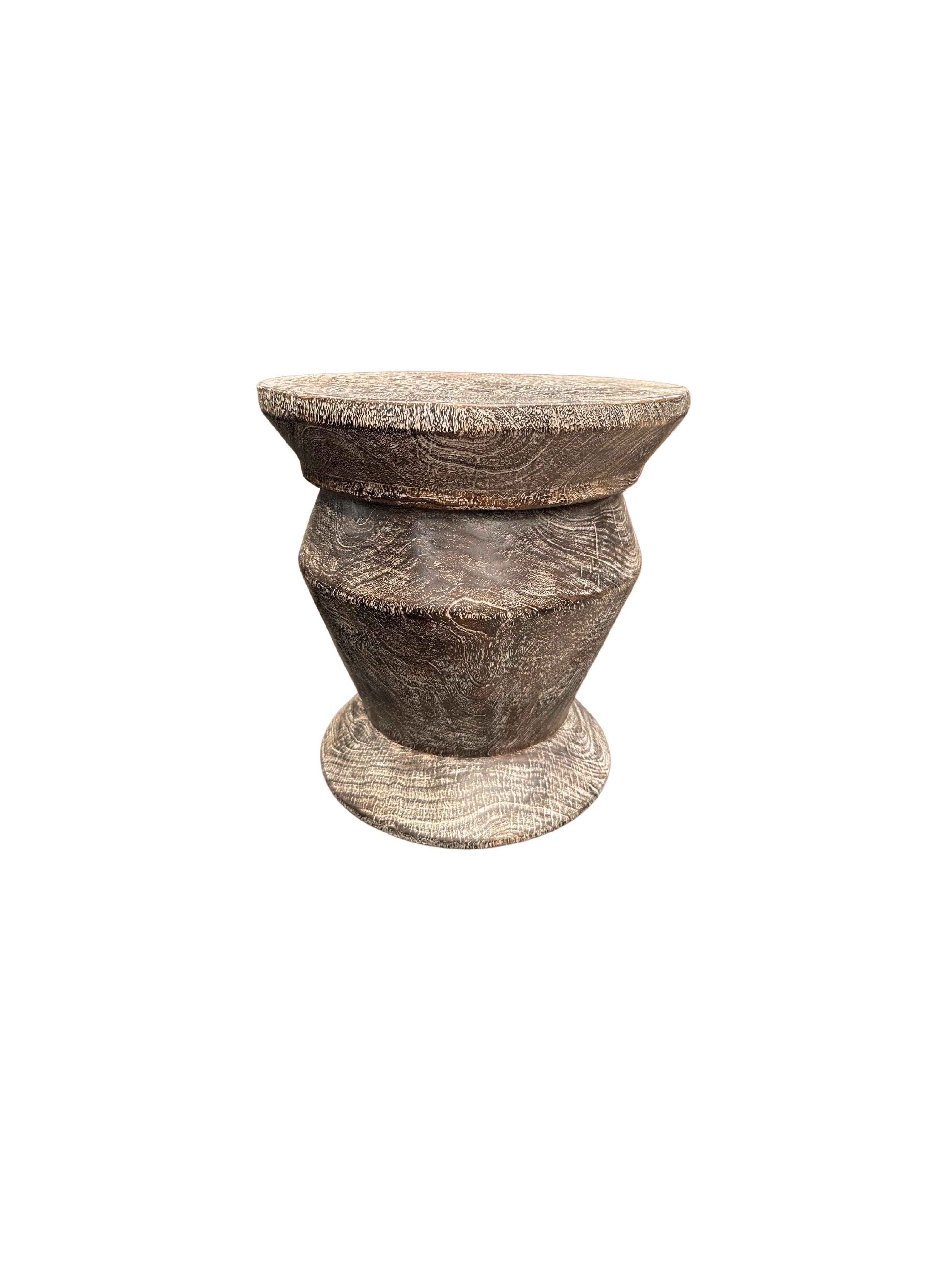 Une table d'appoint merveilleusement sculptée, fabriquée à partir d'un seul bloc de bois de manguier. Il présente de merveilleuses textures de bois. Cette table présente des détails sculptés qui enveloppent ses côtés. Pour obtenir sa finition brun