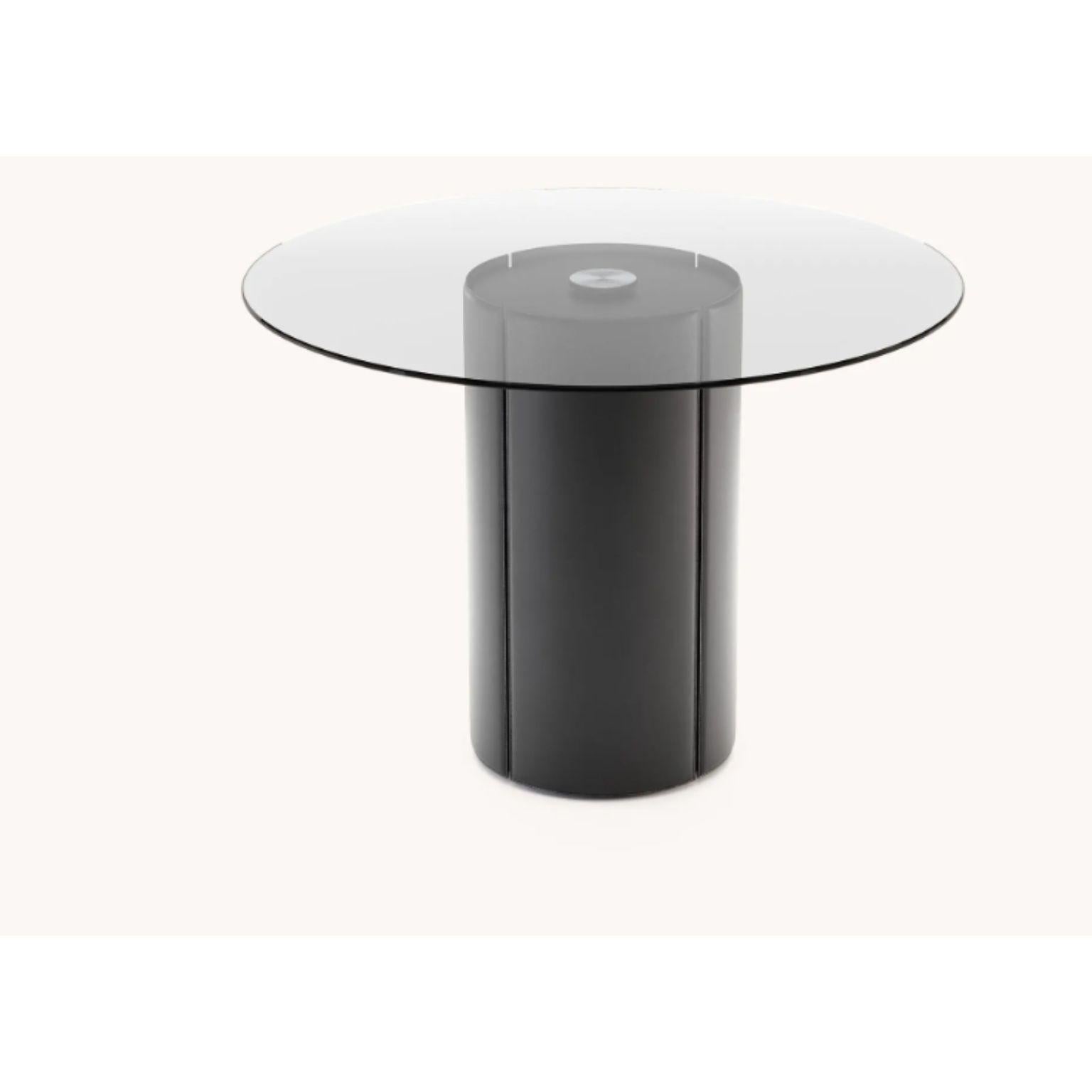 Round Mano dining table by Domkapa
Dimensions: W 140 x D 140 x H 75 cm.
Materials: Black lacquered matte, natural leather (Albany Black), smoked glass.
Also available in different materials.

With classic materials and an outstanding shape,