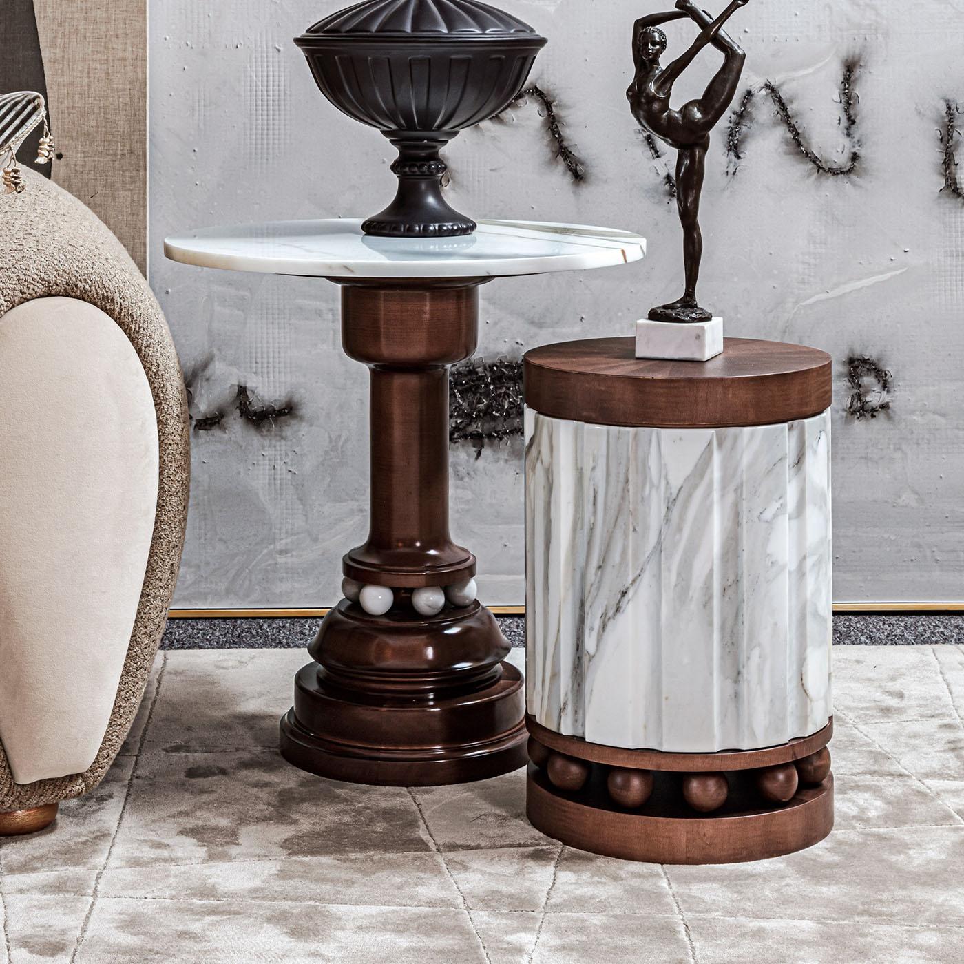 Cette table d'appoint se distingue par sa base en bois massif ornée de marbre. La structure délicate est ancrée sur des sphères de marbre Calacatta Borghini.