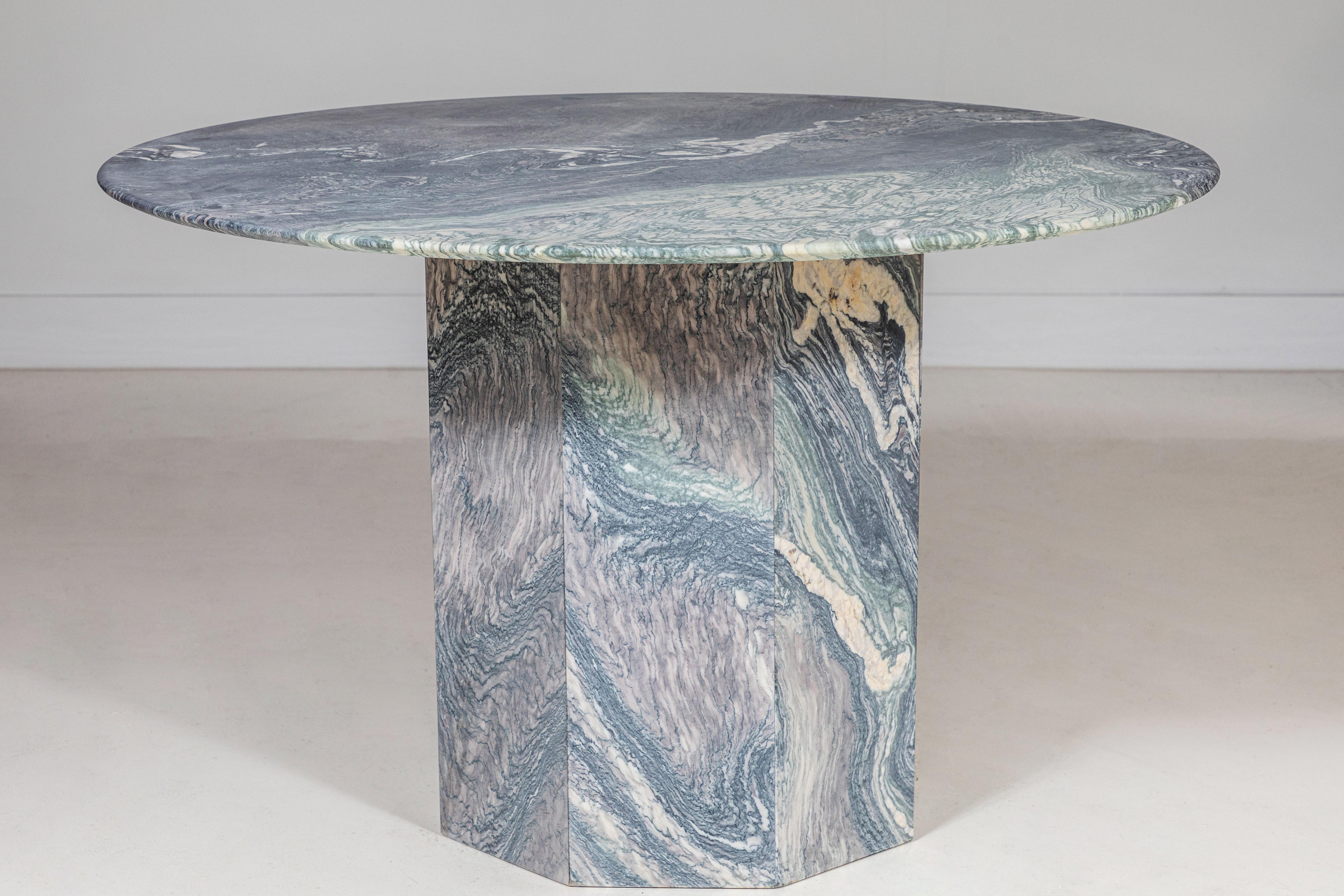 Round matte honed marble table with faceted pedestal base.