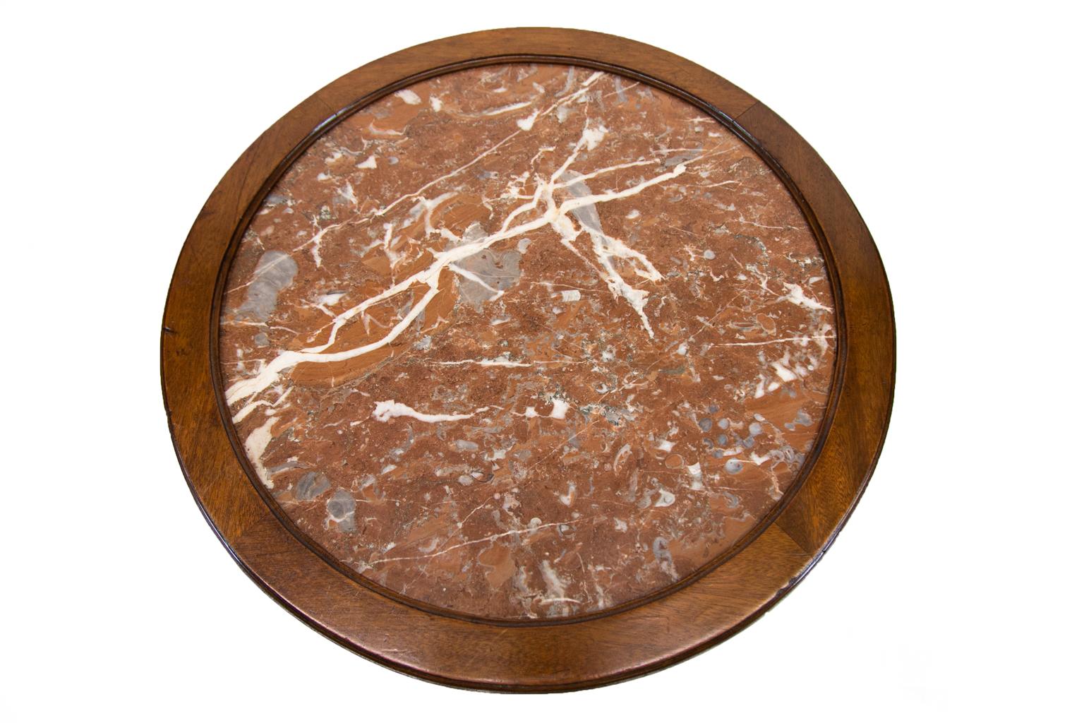 Round marble-top French center table is framed with a molded mahogany border. The apron has applied brass convex moldings framing two opposing drawers and two opposing pullout / pull-out slides that have blind tooled textured leather inserts. The