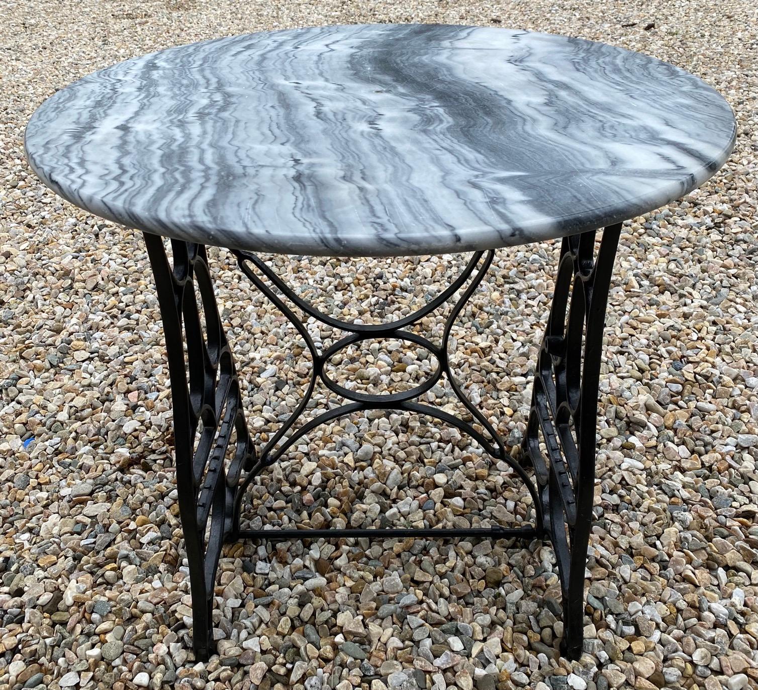 The unique round marble top table has an antique sewing machine base made into a table base. The marble top has beautiful veining. Note it does have a center mark where it is used to attaché to the base. Great as a garden dining table for indoor or