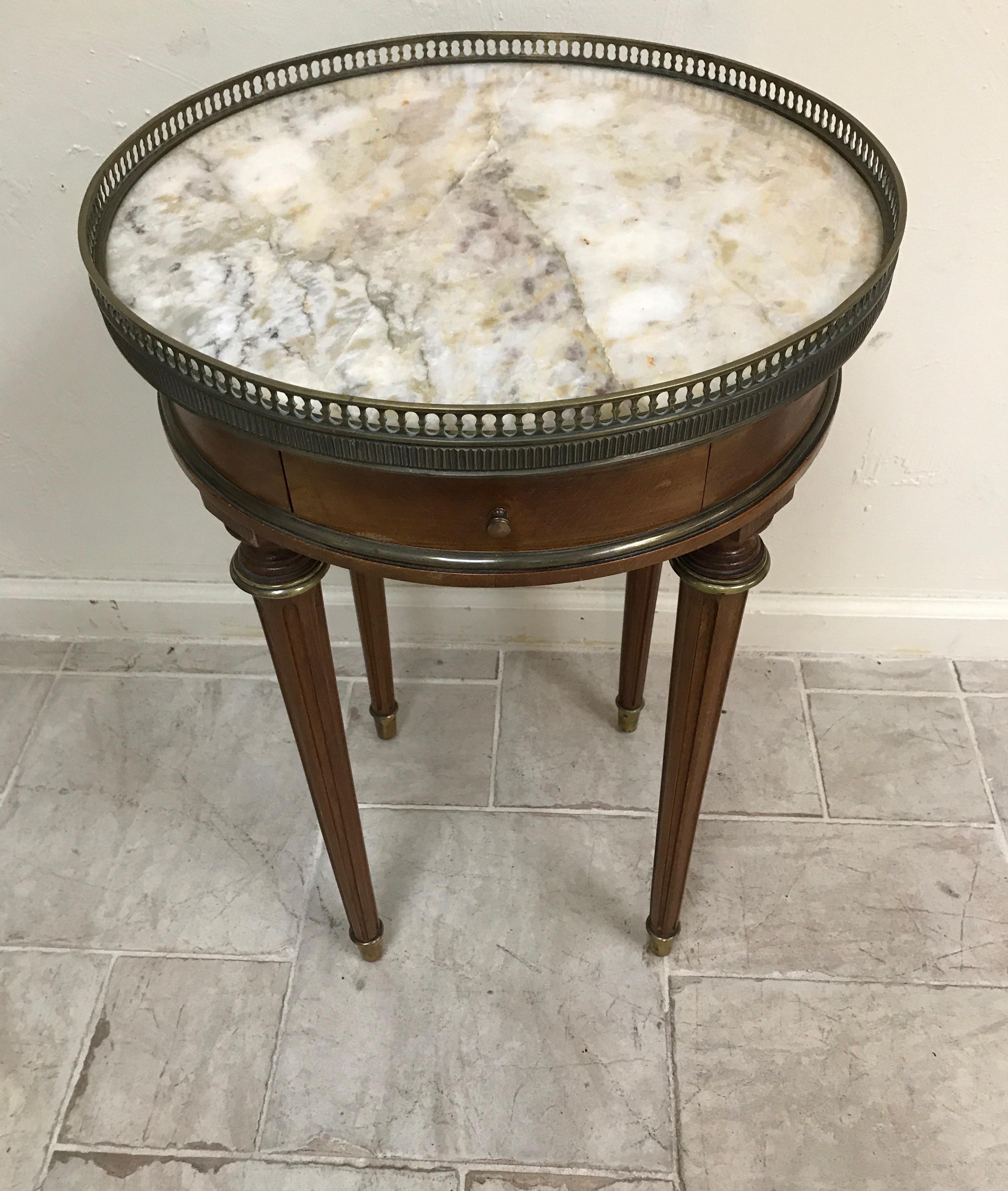 Louis XVI style marble-top end/drinks table with brass gallery and one-drawer.
Marble is white with gold and purple veins.