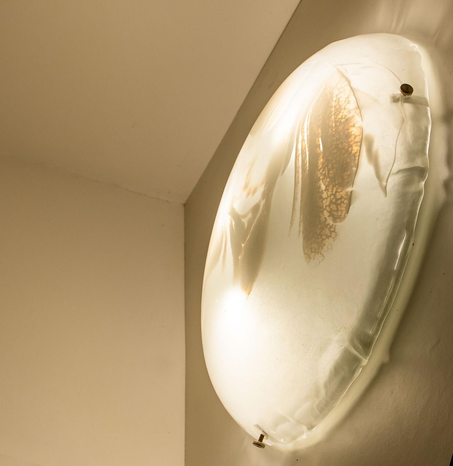 Clean lines to complement all decors.  A wonderful high-end wall light fixture with silver detail and thick marbled blown glass. Manufactured in the 1960s.
The glass of the light fixtures are made of clear textured glass giving the piece a playful