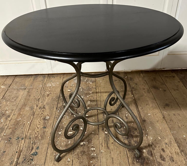 French charming round bistro style table with curved iron base with black ebony stained wood table top. This bistro table will comfortably seat 2.
The curved legs are joined in the center by two rings.
Baroque style