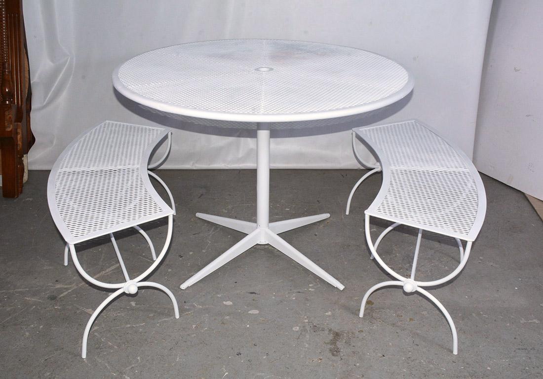 Round steel metal mesh top, wrought iron base dining table with center hole for umbrella by Woodard. Dining height table with two curved quarter round mesh benches and sculpted base suitable for indoor or outdoor patio or garden use. Newly