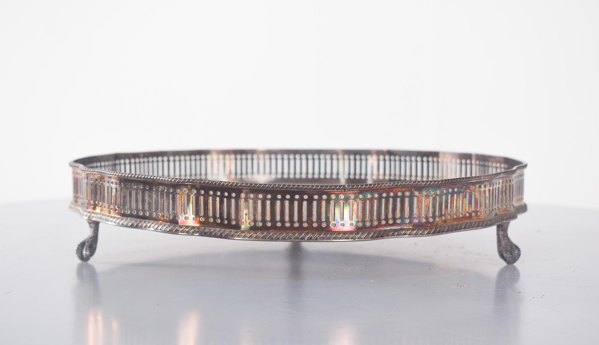 Runder Drahtkorb aus Metall. Leicht gewellte Ränder mit einem zarten durchbrochenen Gitter entlang des Randes. Die Oberfläche des Brettes ist reich verziert mit eingravierten ornamentalen Mustern, darunter Arabesken, Schriftrollen und geometrische