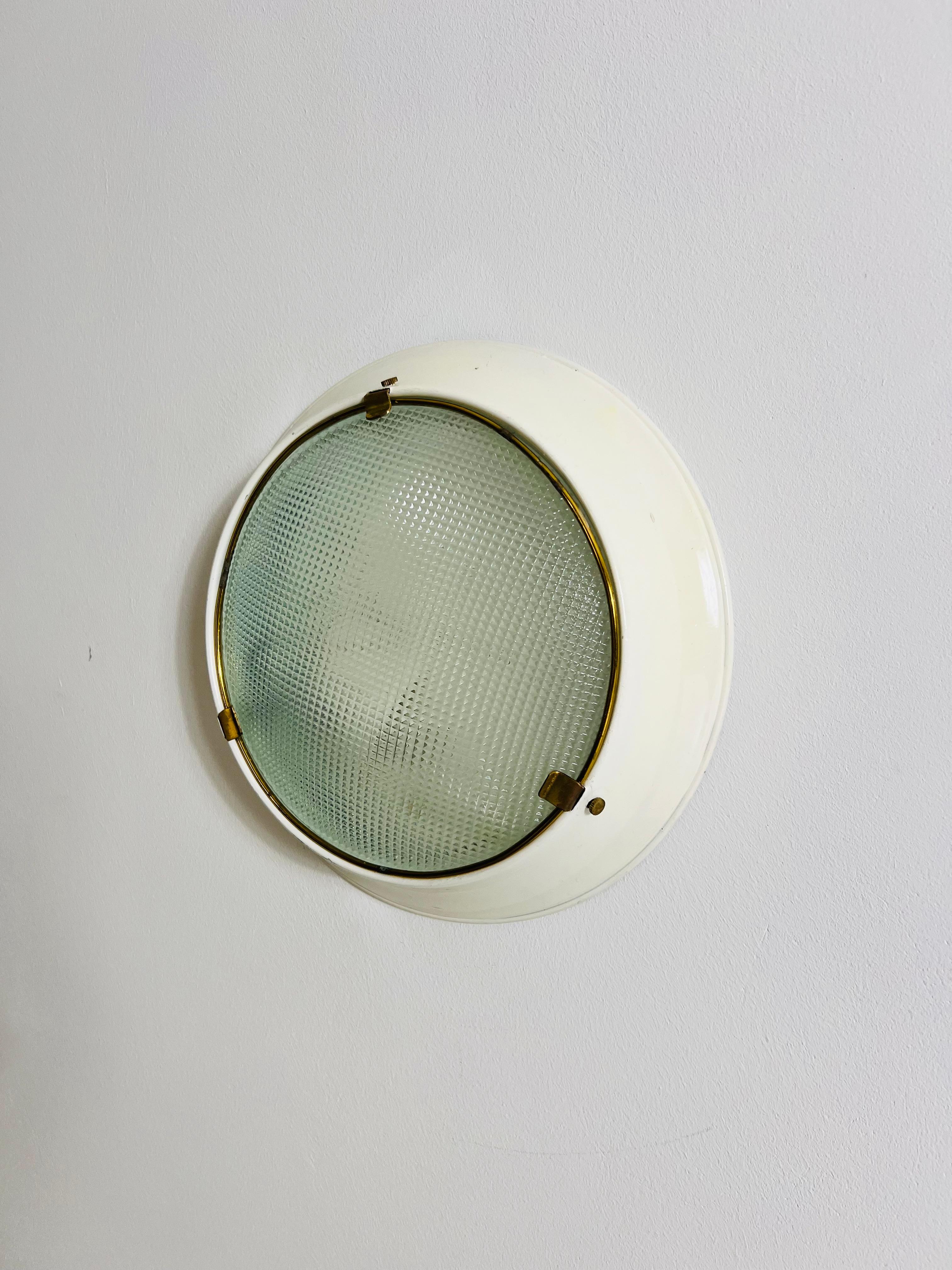 This elegant flush mount by Stilnovo, crafted in 1960s Italy, embodies the timeless sophistication of mid-century design. Featuring a round metal frame in white, accented by a brass inner ring, the lamp combines simplicity with a touch of
