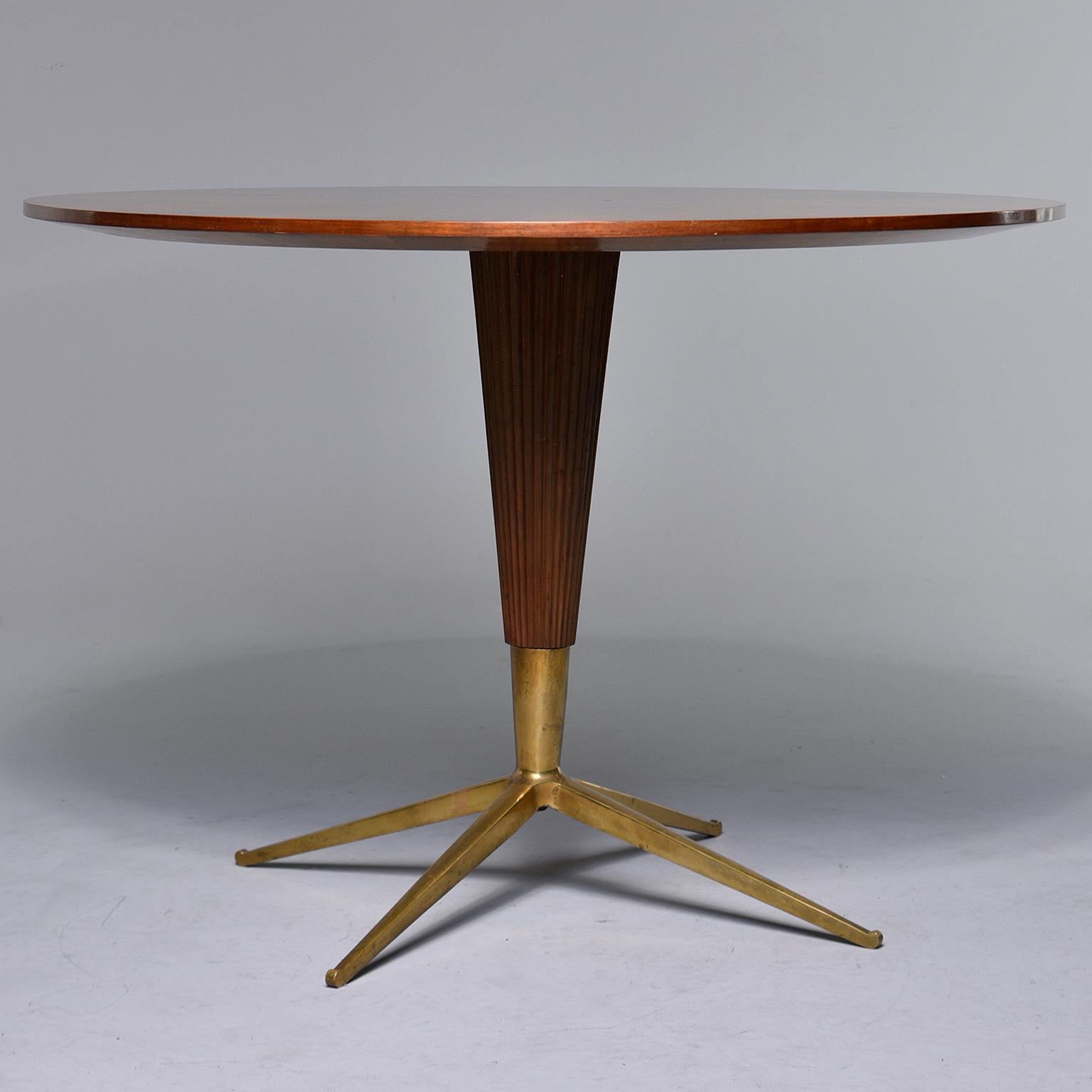 Round Italian table can be used as a center table, breakfast table or game table, circa 1960s. Top features a starburst pattern of what appears to be walnut veneer. Tapered and ridged center support column ends in four legged brass base. Unknown