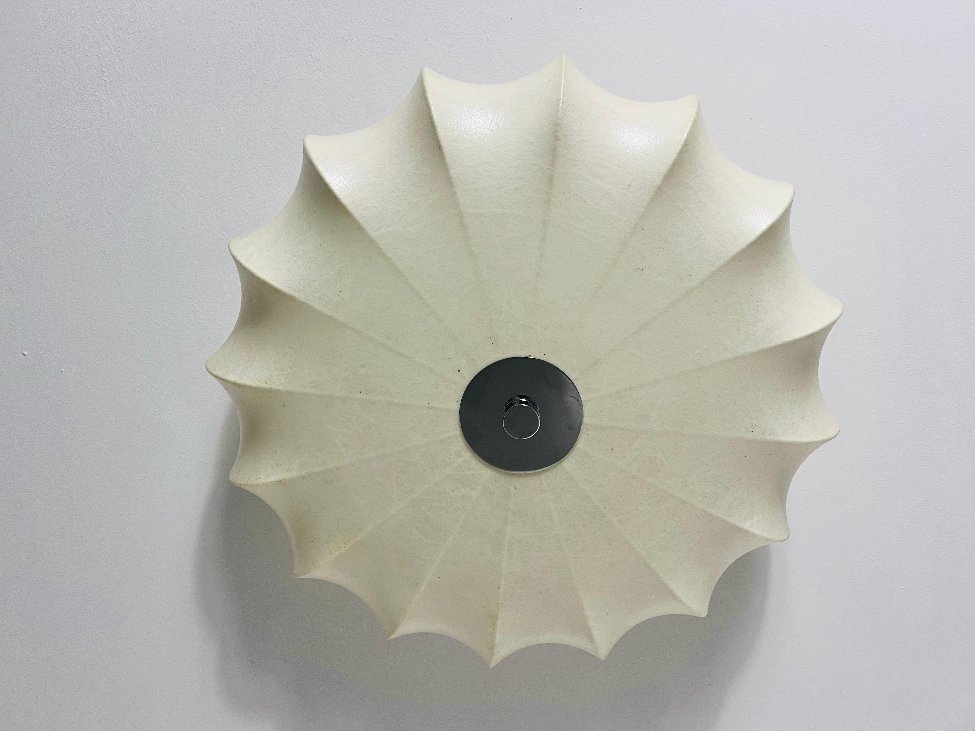 This elegant Cocoon ceiling lamp, crafted in Italy during the 1960s, embodies the sleek and timeless style reminiscent of renowned designer Achille Castiglioni. Its sophisticated round form gently tapers outward, creating a striking silhouette that