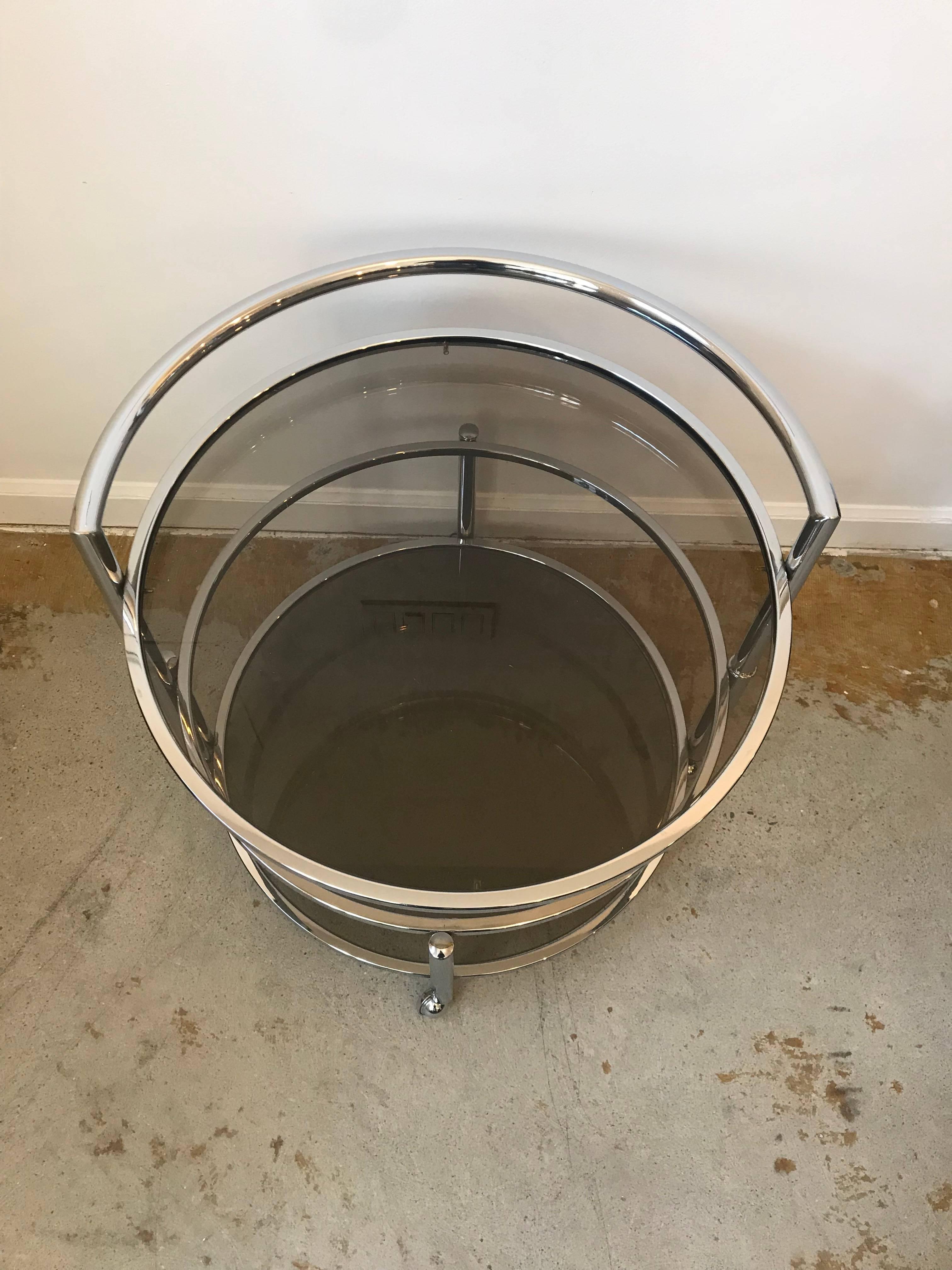 Very cool Mid-Century Modern two-tier round side or coffee table that expands if desired. Chrome frame with smoked glass, on castors. Very similar to the designs of Milo Baughman.