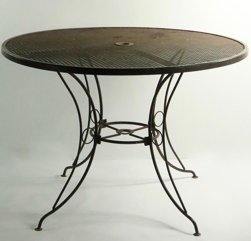 Round wrought iron and metal mesh dining table attributed to Woodard. This table was originally designed for outdoor, poolside, patio, garden use, but is also suitable for interior and or on a porch etc. Currently in later brown paint finish, we