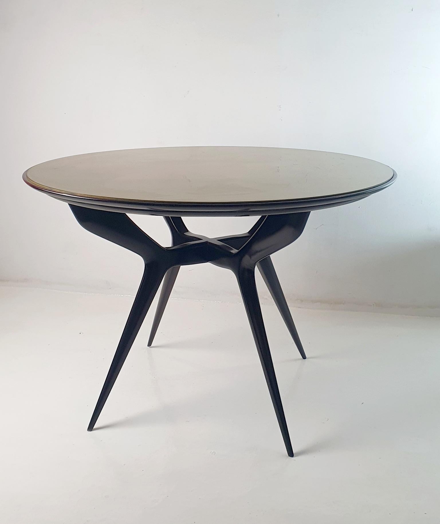 Fabuleuse table de salle à manger ronde au design organique avec un plateau en verre doré. Produit en Italie dans les années 1950 à la manière d'Augusto Romano. Les pieds, d'une grande qualité artisanale, sont reliés au centre, ce qui confère à la