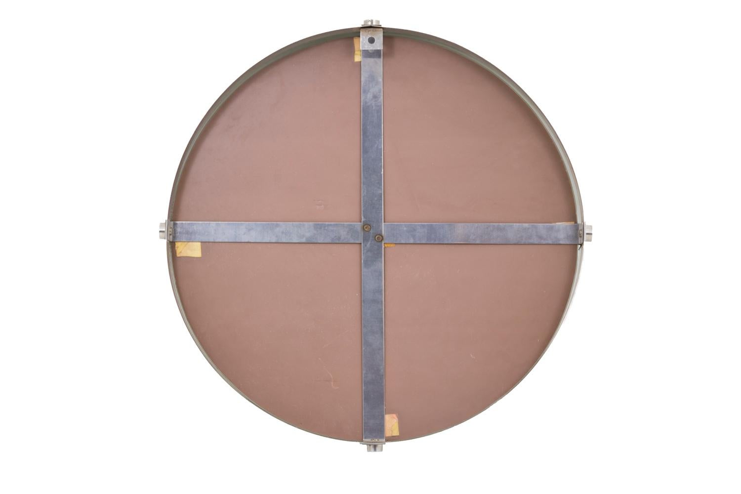 Round mirror in brushed stainless steel with a frame with a depression.

Work realized in the 1970s.