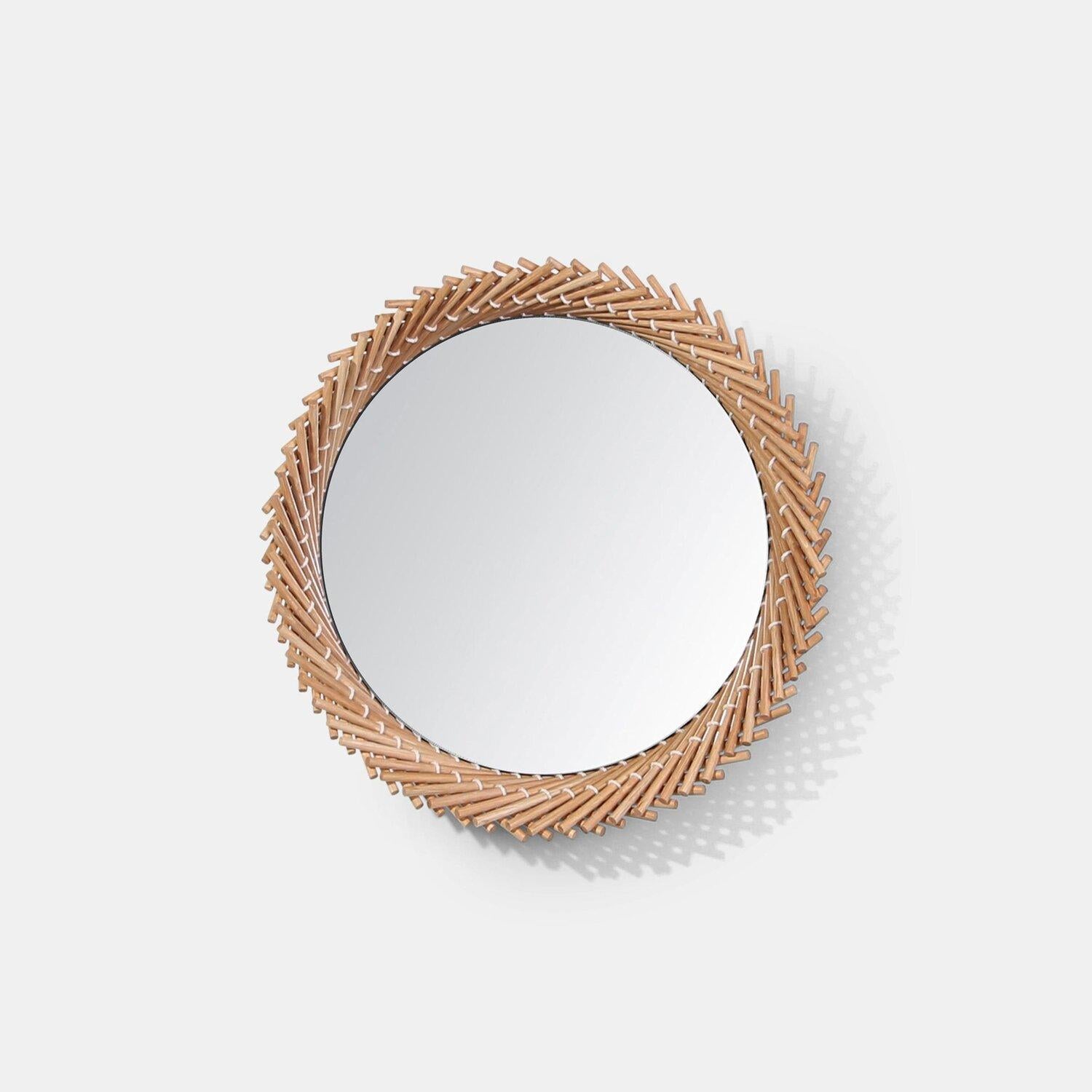 The Mooda Mirror is composed of a set of dowels stitched together to create a beautiful geometric edge around the glass. The mirror in turn reflects the dowels along its circumference, completing the traditional form of the Mooda.   Available in two