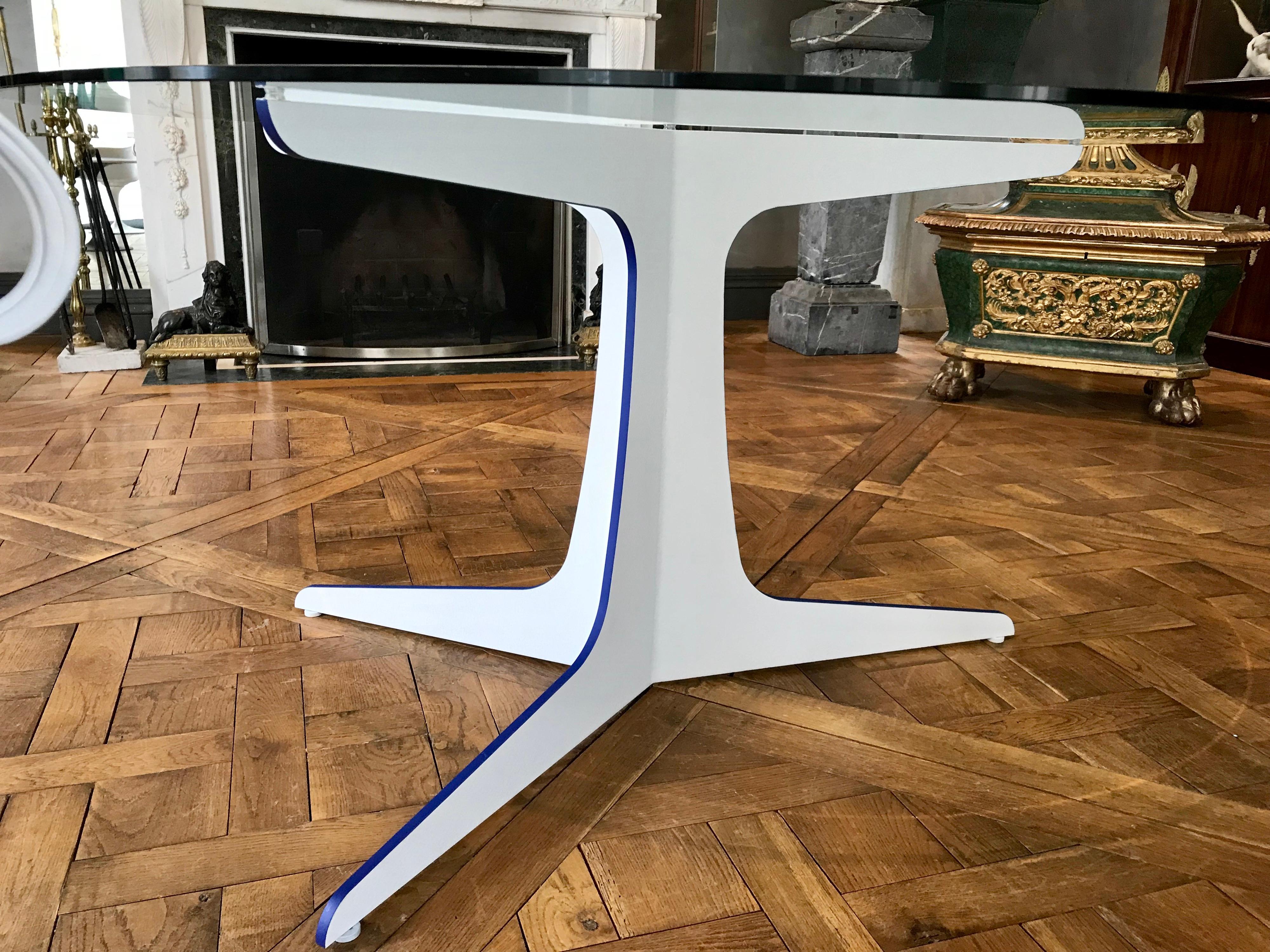 This unique 53” round modern glass top dining table has a three sided laser cut steel base shaped like a tree trunk.
It is powder coated in white and has striking azure blue accents on the edges.
The powder coating process makes it rust and damage
