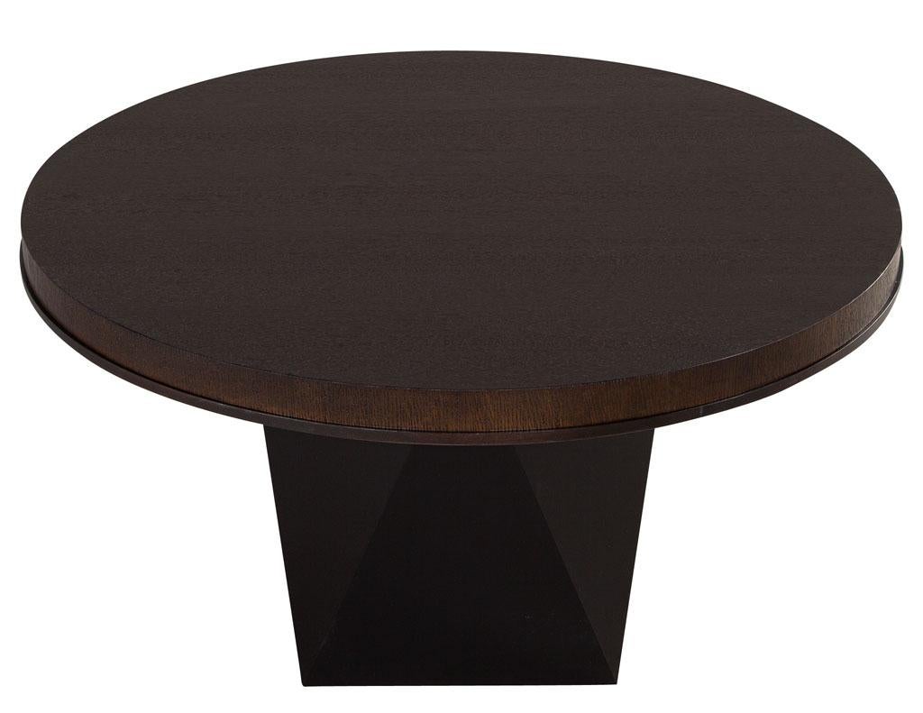 Round modern oak dining table with black geometric base. Unique wire brushed oak top in an espresso brown satin finish with thin black edge detail matching the base. Completed with a modern unique geometric base in satin black finish. Perfect size