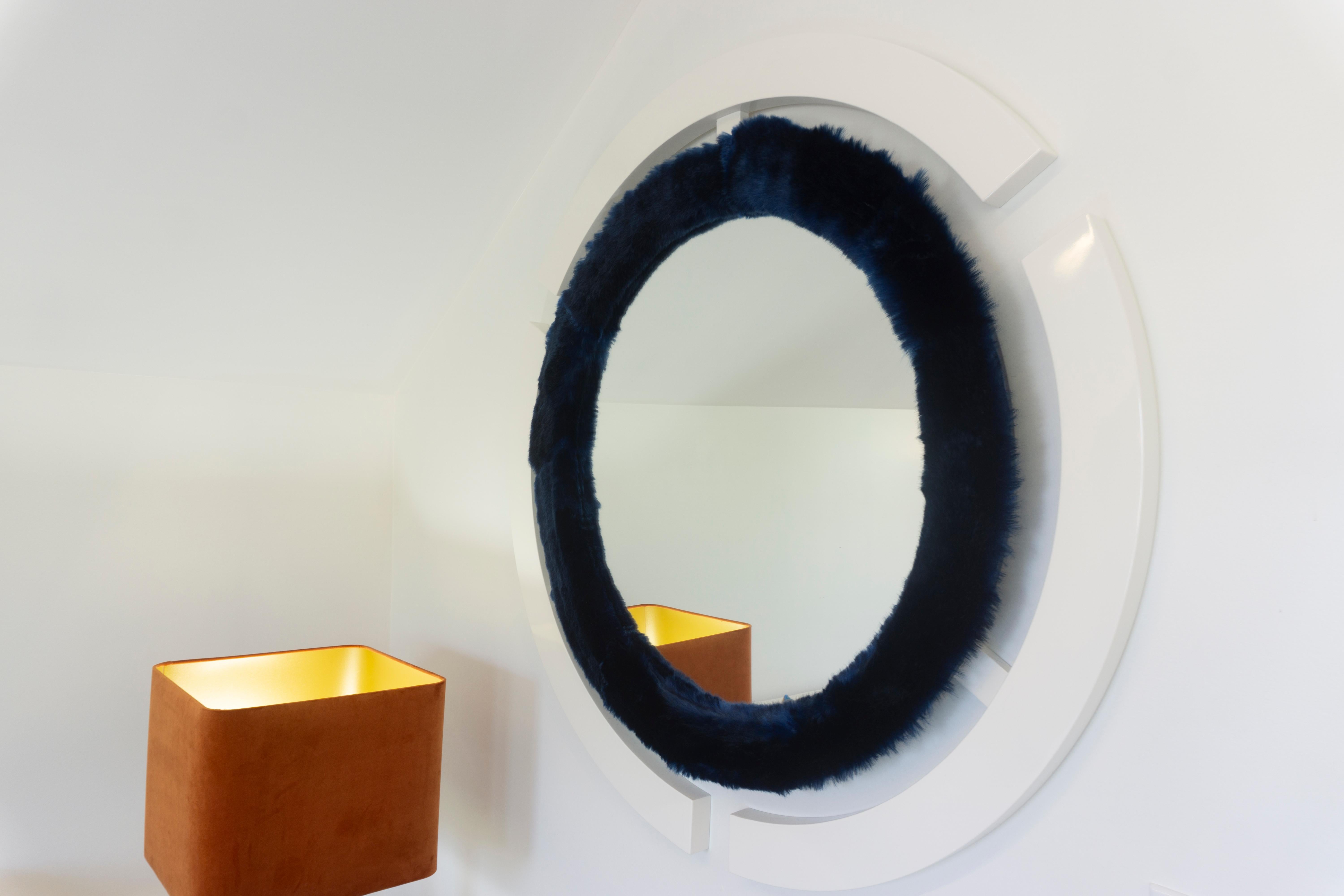 Ein moderner, handgefertigter runder Wandspiegel, inspiriert vom Space Age-Dekor mit einem wilden Twist. Der Glasspiegel ist mit Kaninchenfellimitat und einem weiß lackierten Rand eingefasst. Sondergrößen und -ausführungen sind auf Anfrage