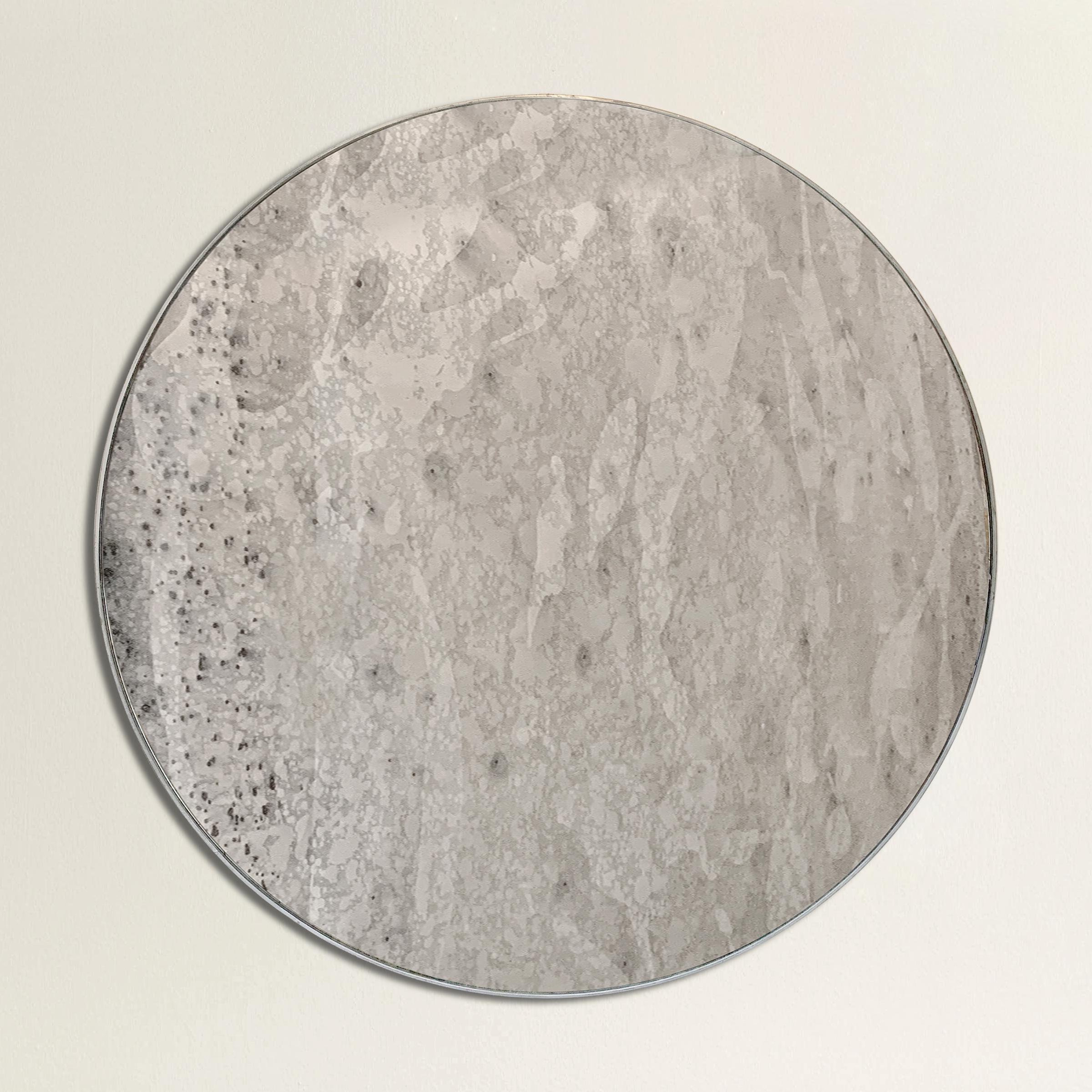 A wonderful large round mirror with a galvanized steel frame and with an antiqued glass that mimics the texture of the moon.