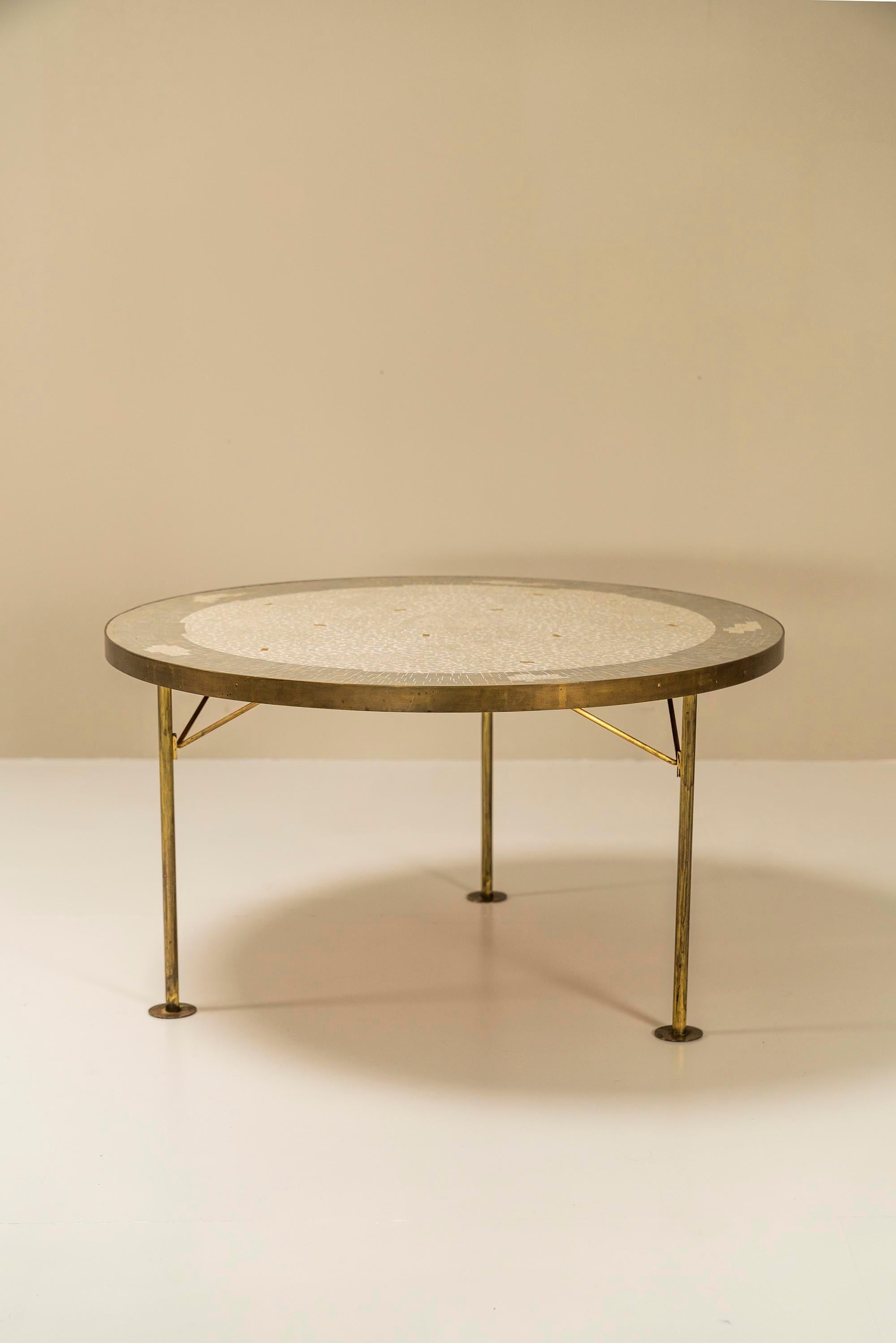 Nice Round Mosaic coffee table by Berthold Müller-Oerlinghausen from Germany, ca 1960s. This mosaic coffee table has a brass frame with three legs. The mosaic top has an abstract pattern is a mix of white yellow and grey stones. All his impressive